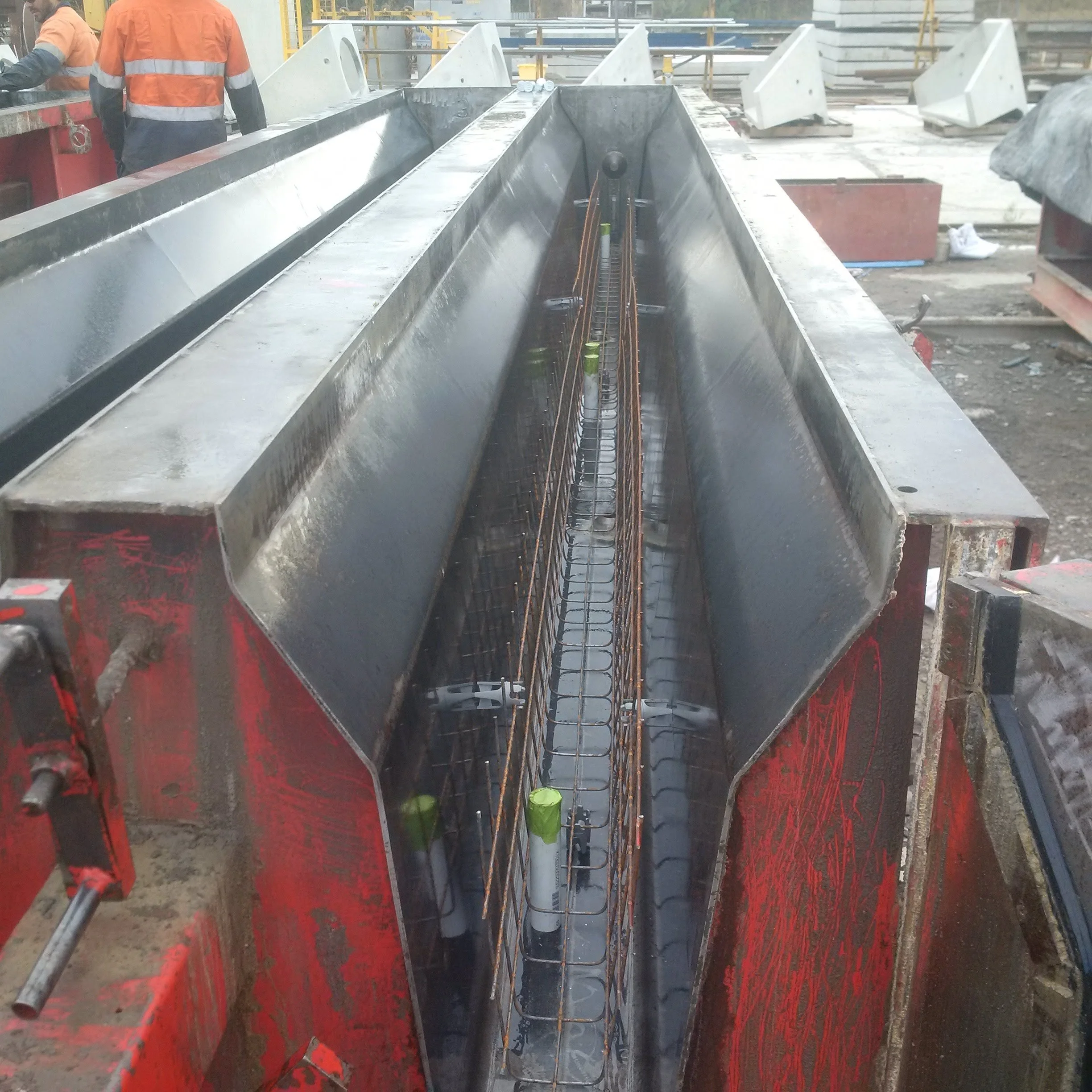Close-up view of a large industrial mold with steel reinforcement bars inside, used for construction of concrete infrastructure at a construction site.