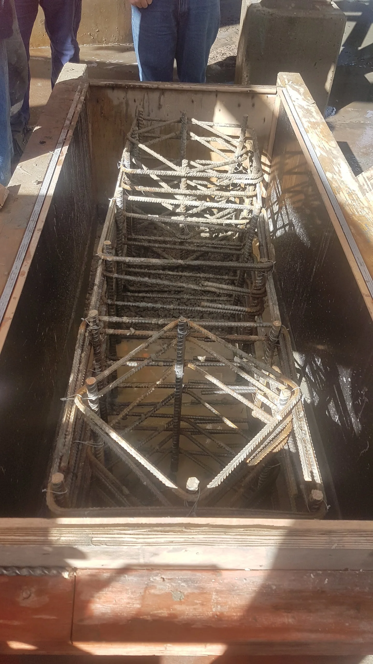 Steel reinforcement rebar framework inside a concrete form for a foundation or structural element at a construction site.