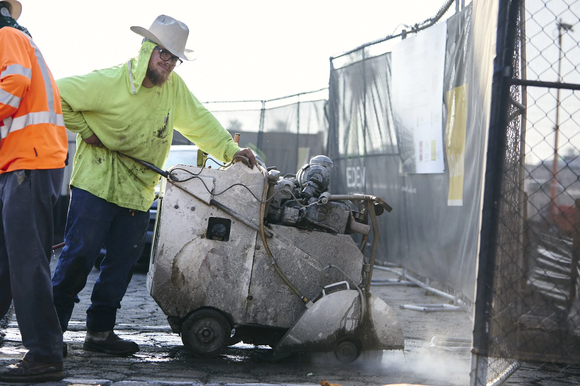 Soff-cut operator cutting asphalt and concrete, construction progress photography