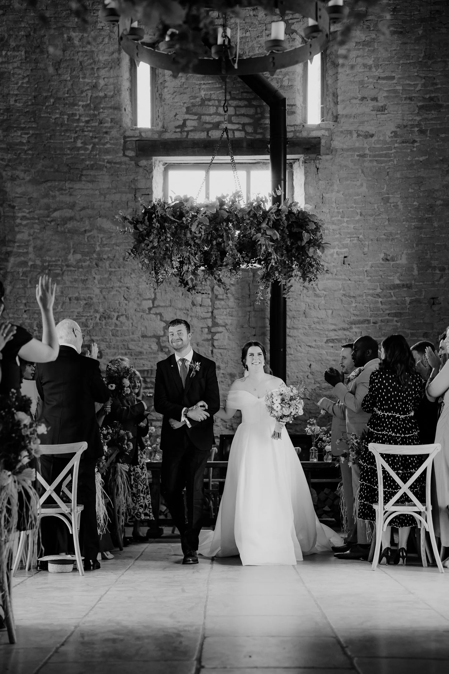 Wedding Photography of the Bride and Groom walking down the aisle at Old Gore Barn, Cirencester, taken by photoJMO