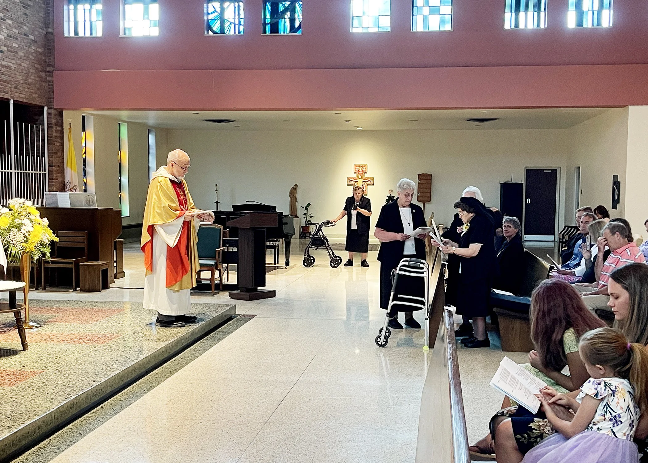  Father Richard Zelik watches as Sister Cecilia Jacko renews her vows during her 75th Jubilee Mass on July 13, 2024. 