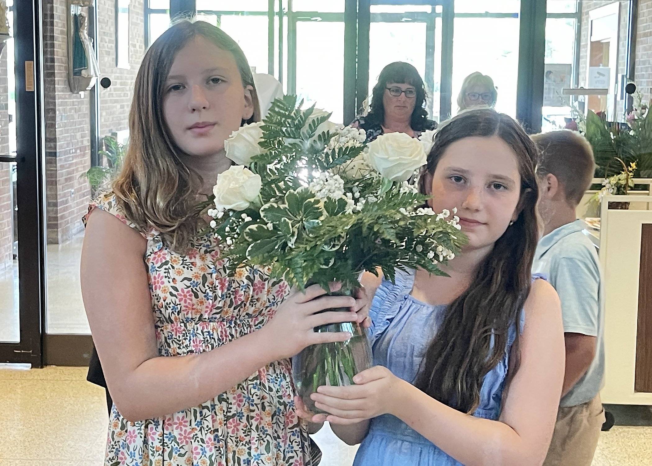  Cora Russell and Lucy Dallvechio, great-great nieces of Sister Cecilia Jacko, carry flowers in memory of deceased Sisters during Sister Cecilia's 75th Jubilee Mass on July 13, 2024. 