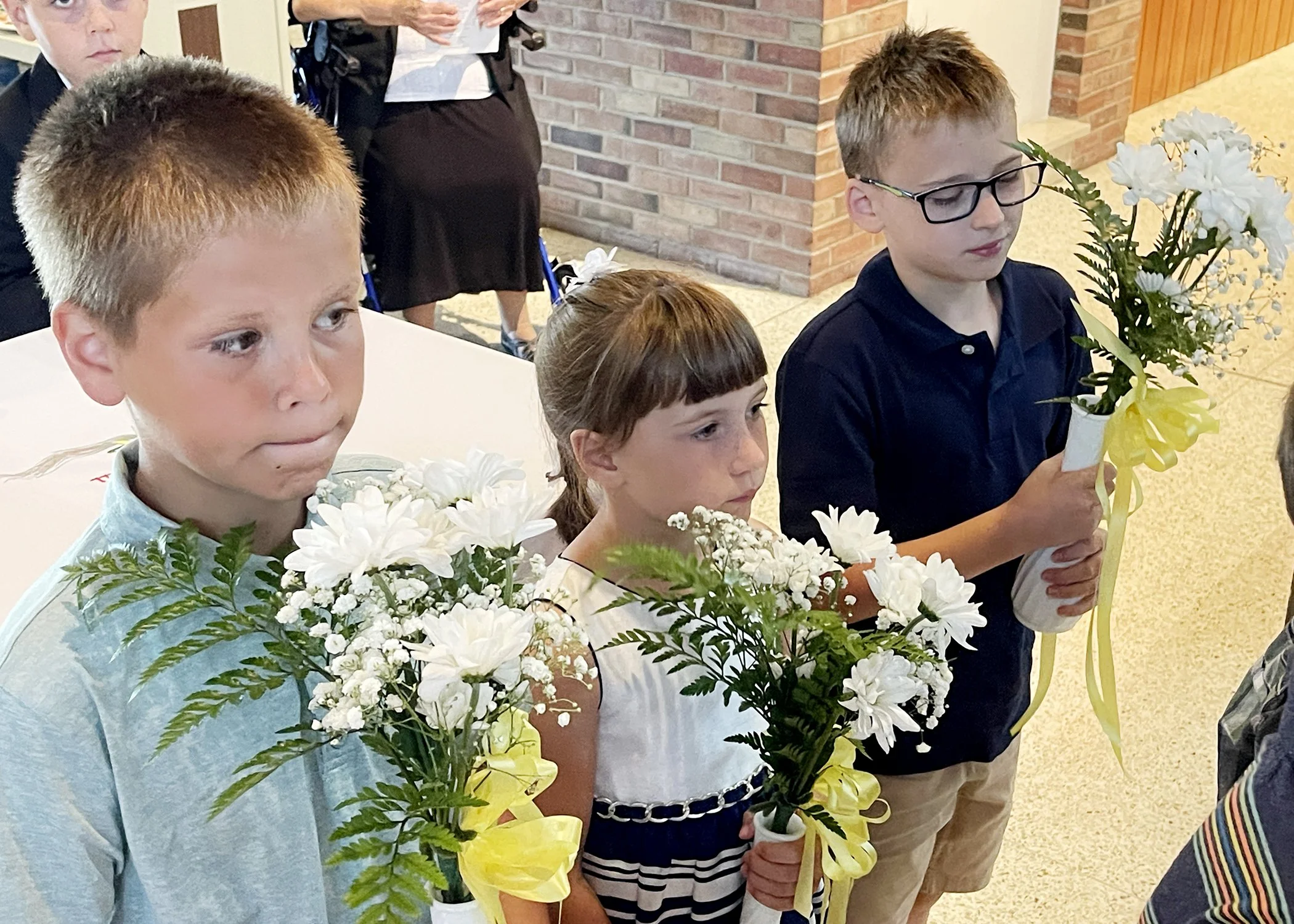  Young members of the Jacko Family carry daisies in memory of deceased family members during Sister Cecilia Jacko's 75th Jubilee Mass on July 13, 2024. 
