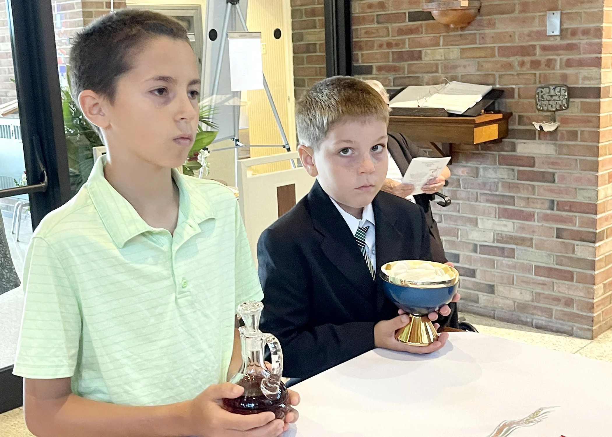  Dominic Guzur and Isaac Guzur, great-great nephews of Sister Cecilia Jacko, participate in the offertory procession during Sister's 75th Jubilee Mass on July 13, 2024. 