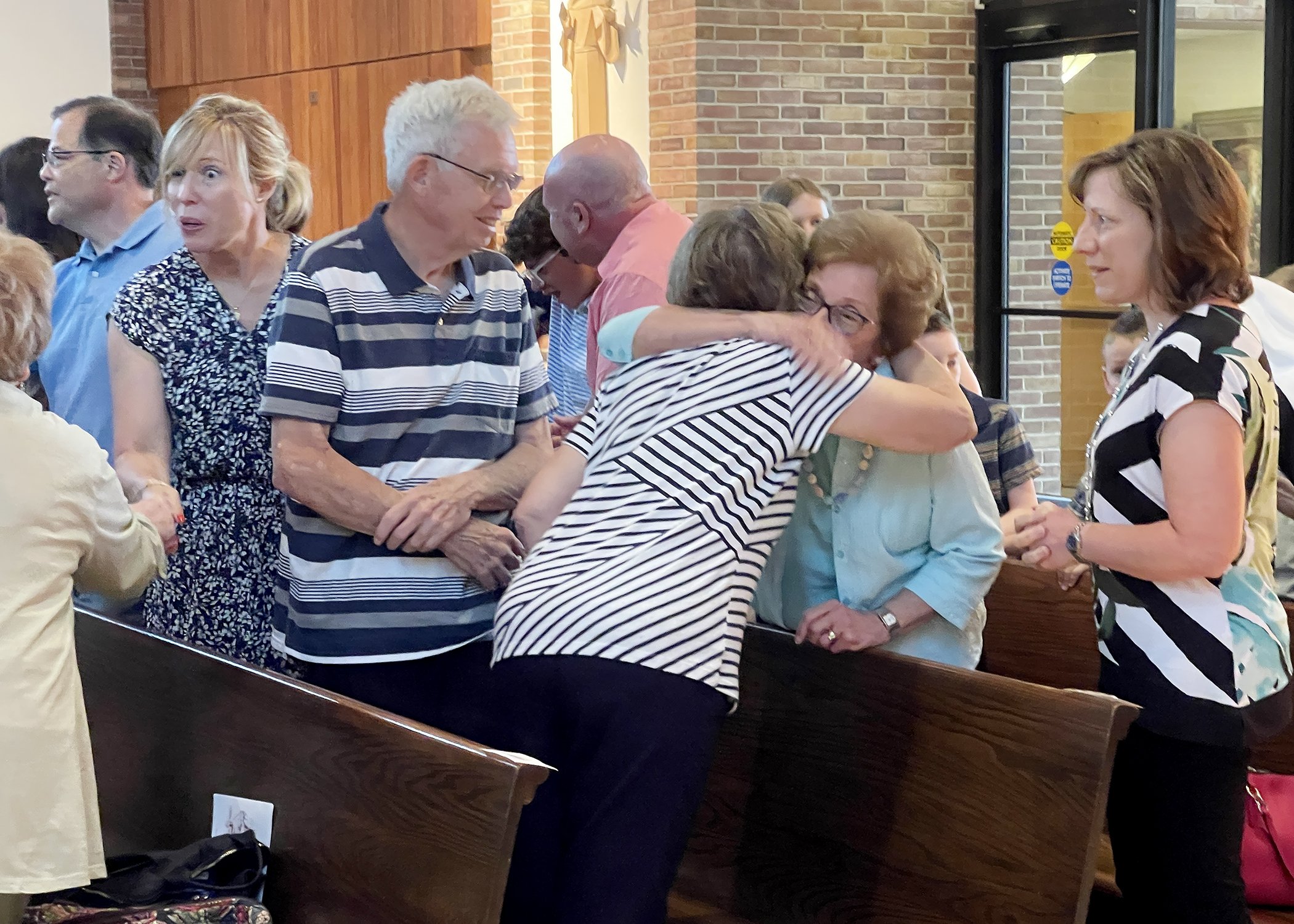  Members of the Jacko Family offer each other peace during Sister Cecilia Jacko's 75th Jubilee Mass on July 13, 2024. 