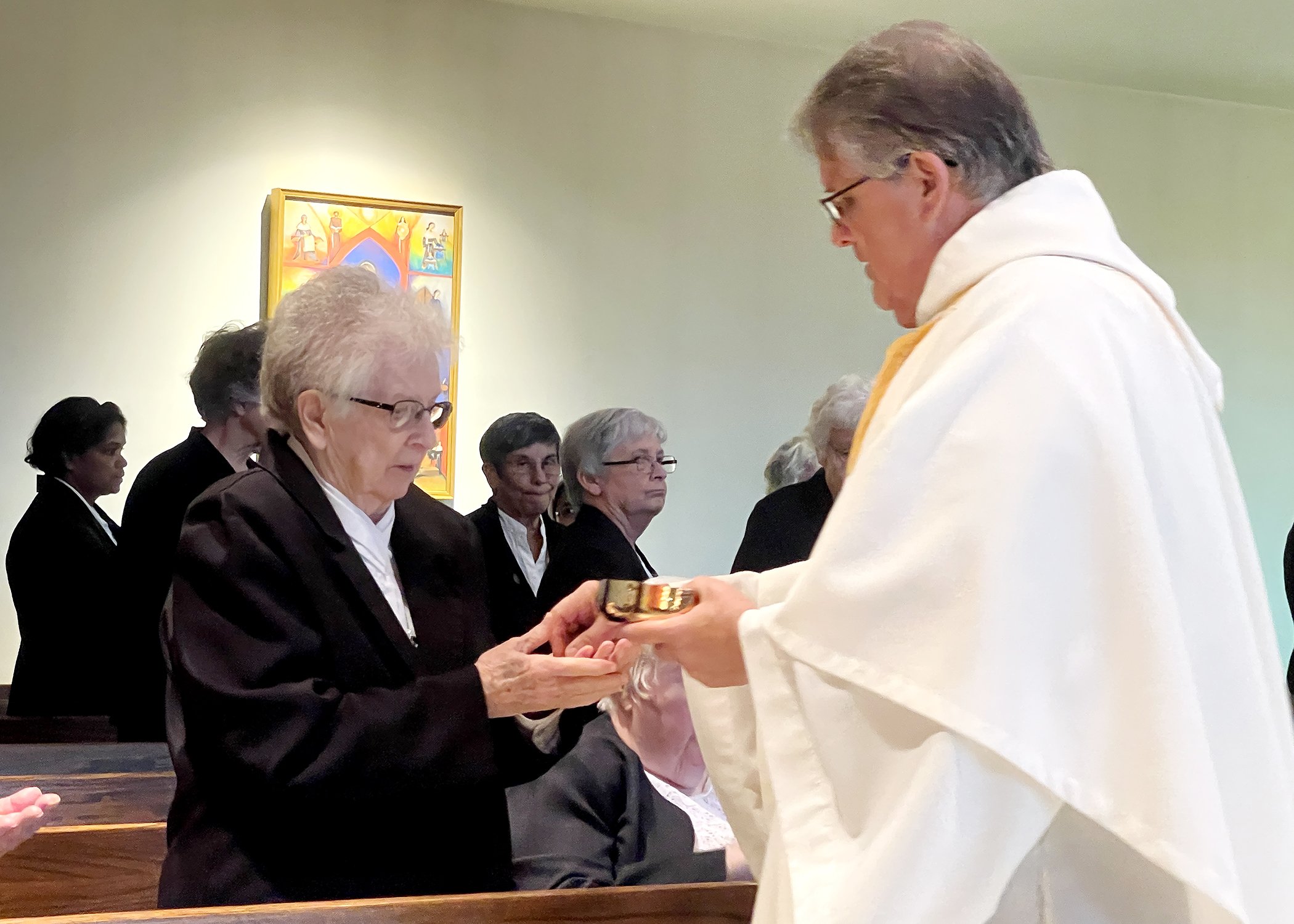  Sister Bernadine Marie Stemnock receives Communion from Father John Bachkay during Sister Cecilia Jacko's 75th Jubilee Mass on July 13, 2024. 