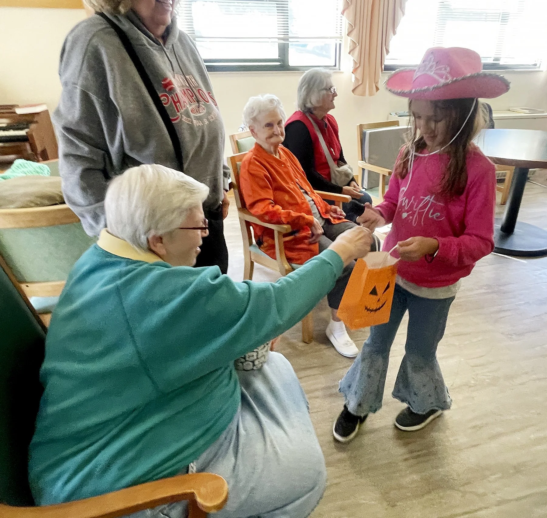  Sister Anece Salay shares some sweets with a Swiftie (a youngster dressed as Taylor Swift) during a Halloween parade at Mt. Assisi Place on October 16, 2024. 