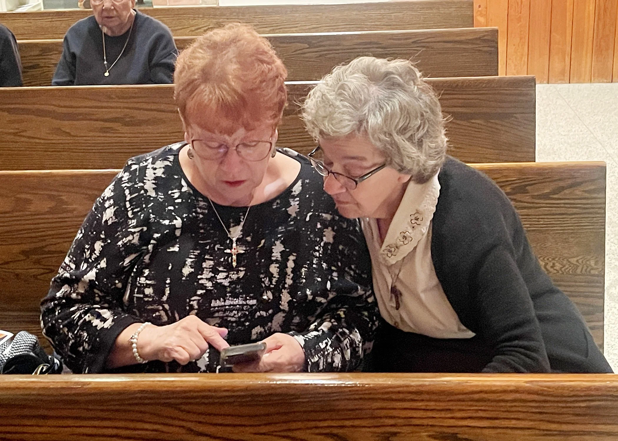  Sister Mary Lou Metro views photos on her niece’s phone following the 2024 Memorial Service at Mt. Assisi Place on November 7, 2024. Sister Mary Lou’s sister-in-law, Helen Metro, was among those prayerfully remembered. 