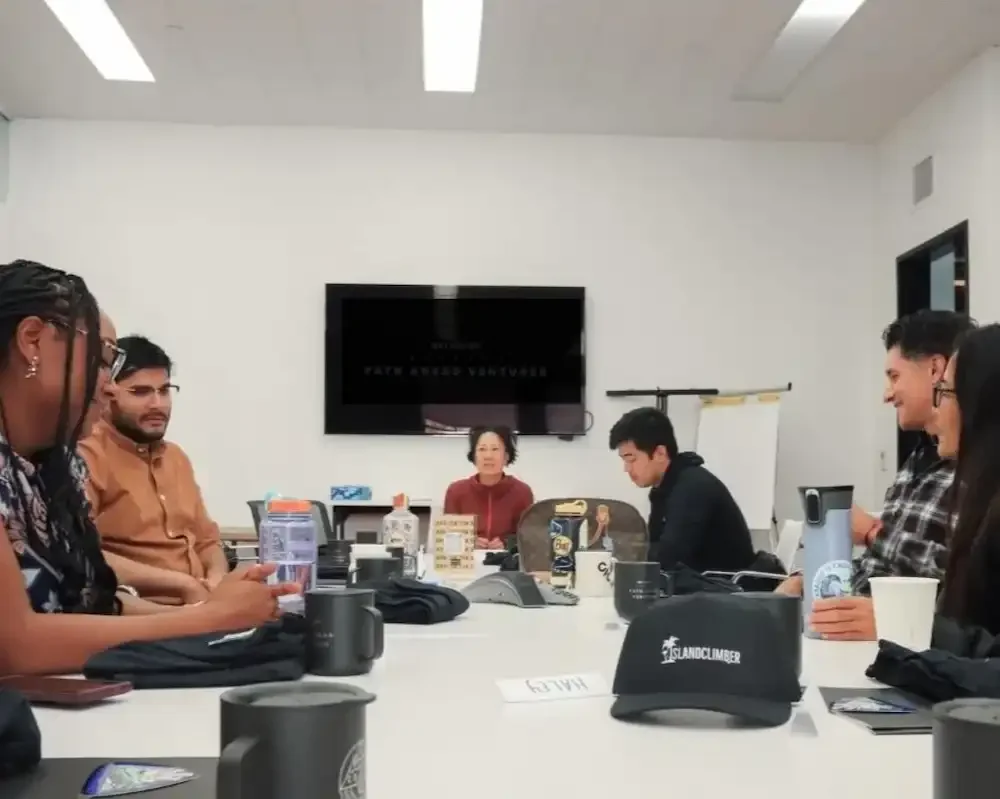 6 people sitting around a table having an outdoor business meeting