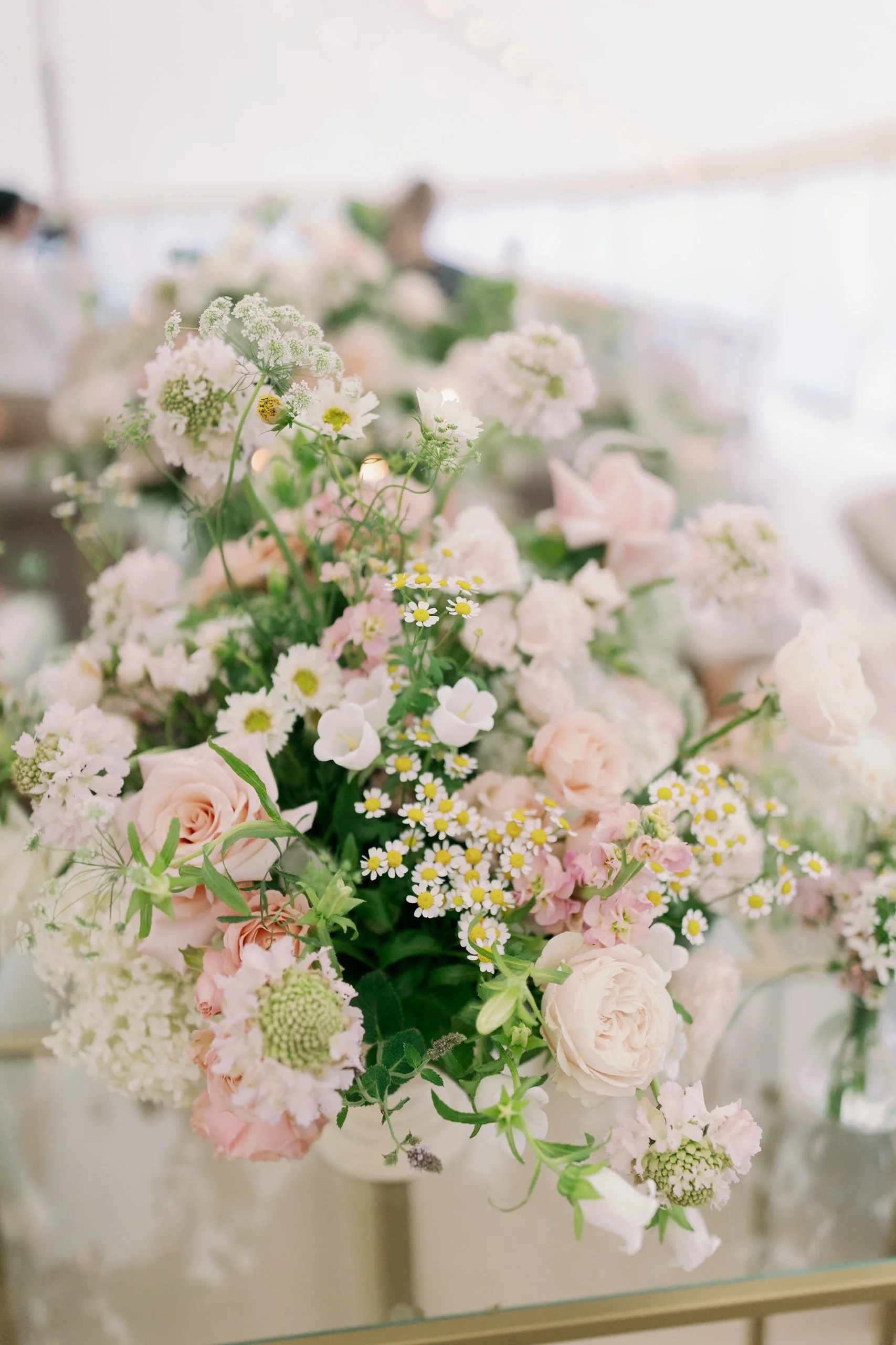 A arrangement of pastel pink and white flowers including roses, daisies, and other wildflowers.