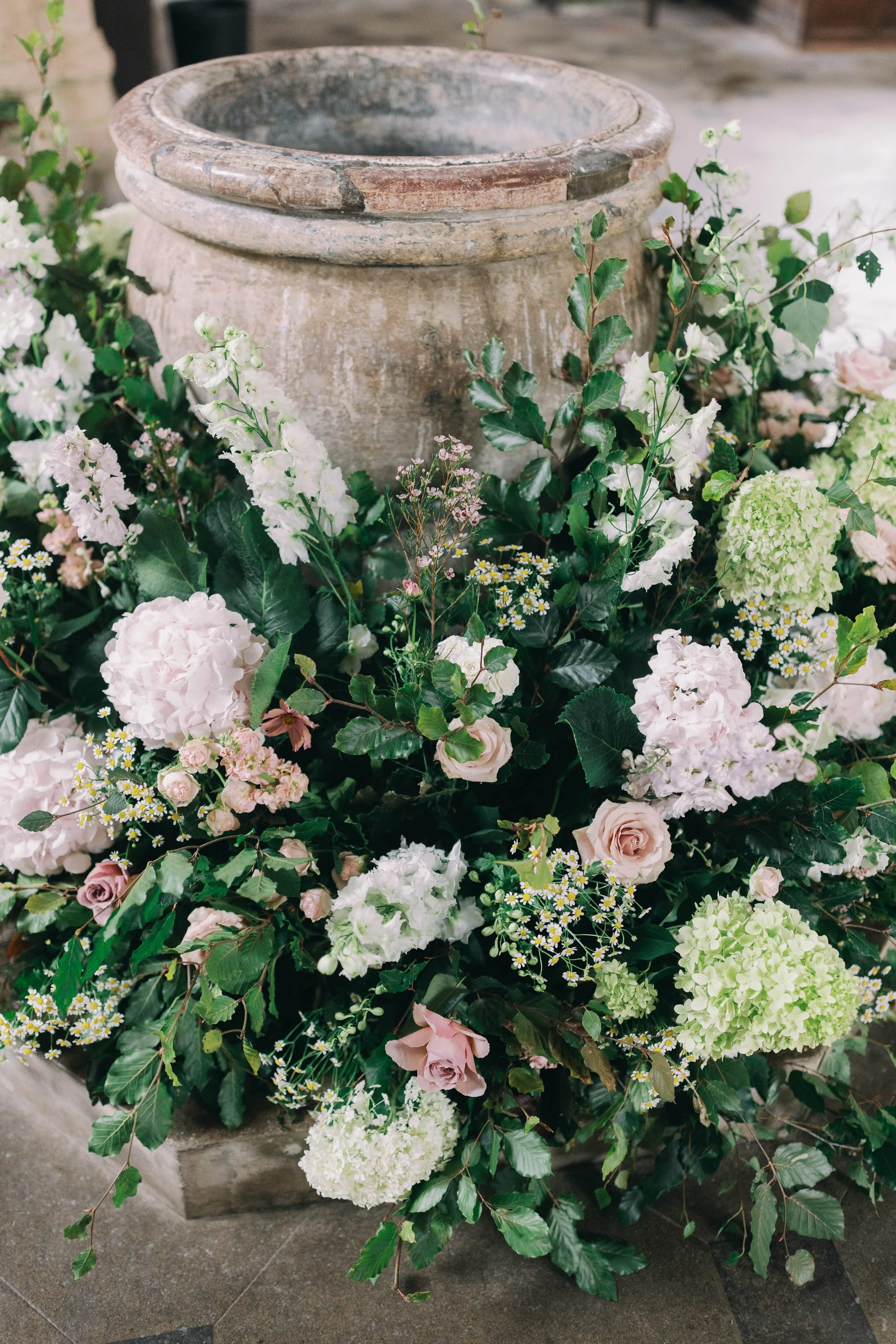A font arrangement with pink and white hydrangeas, roses, and various greenery.