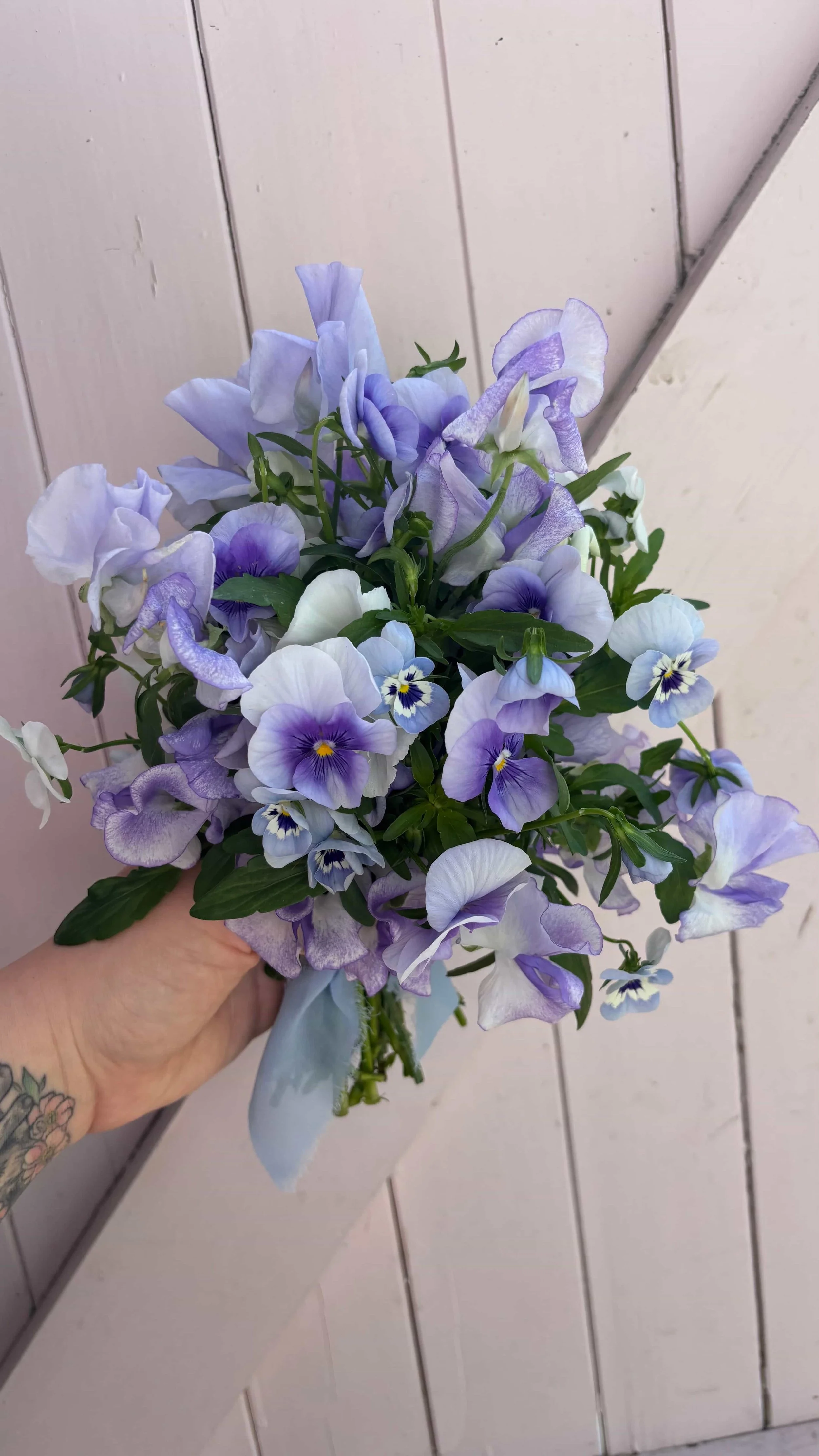 Delicate blue and lilac bridesmaid bouquet with sweet peas and pansies