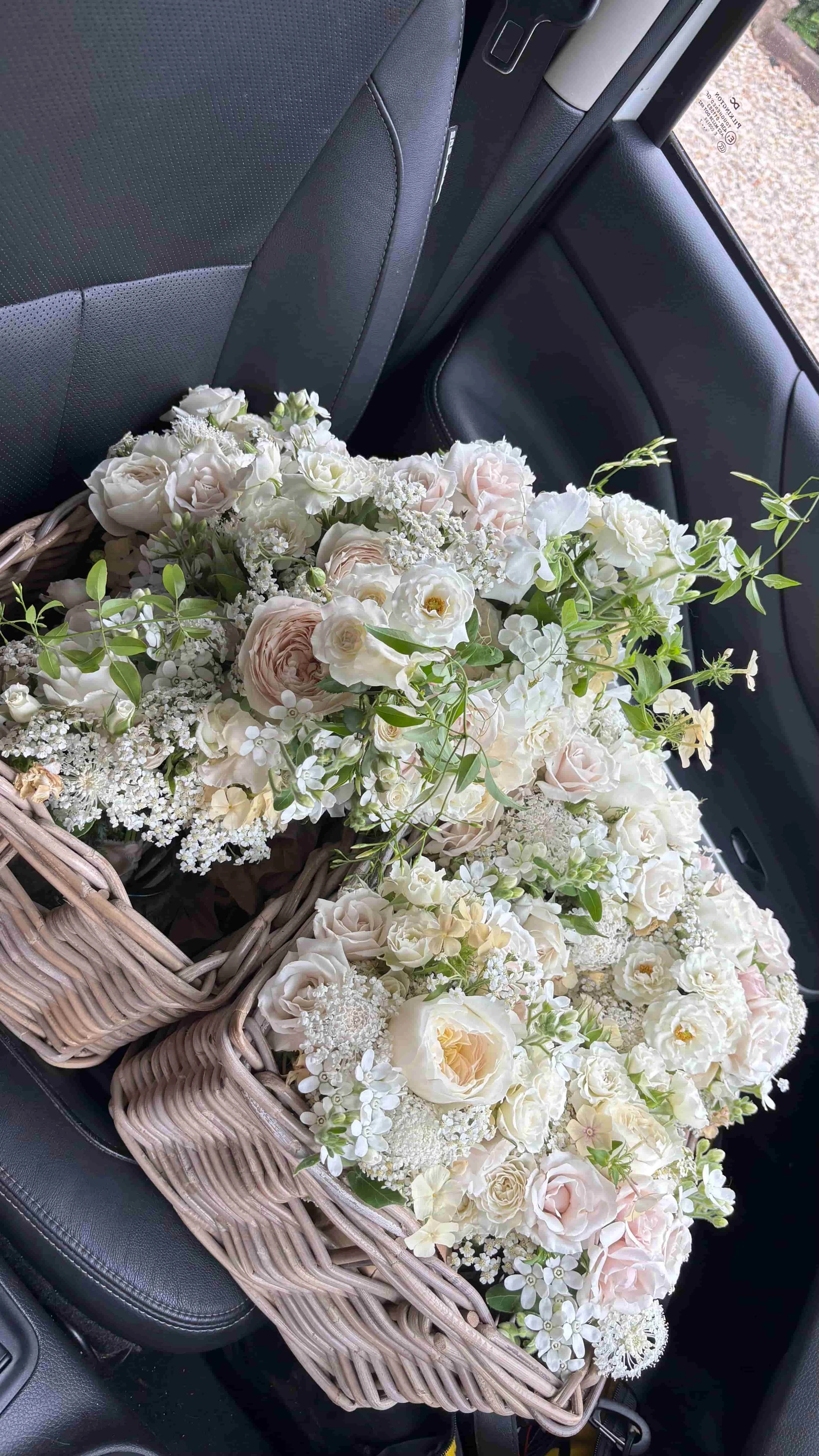 Finished white and blush wedding flower arrangements packed into baskets ready for transport to the venue in Norfolk