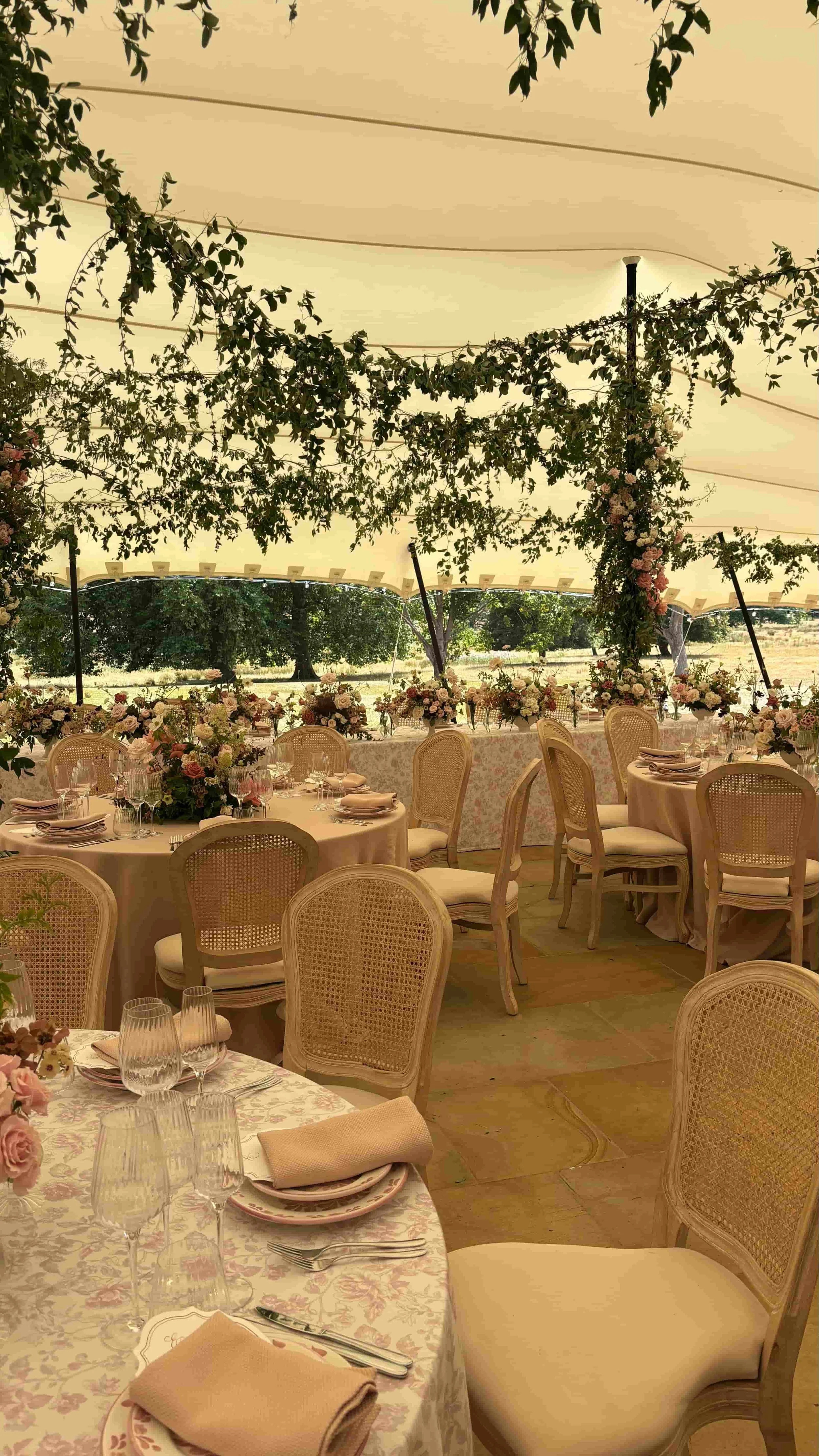 Luxury marquee wedding reception at Wilderness Reserve with climbing roses, overhead greenery and garden-style table flowers