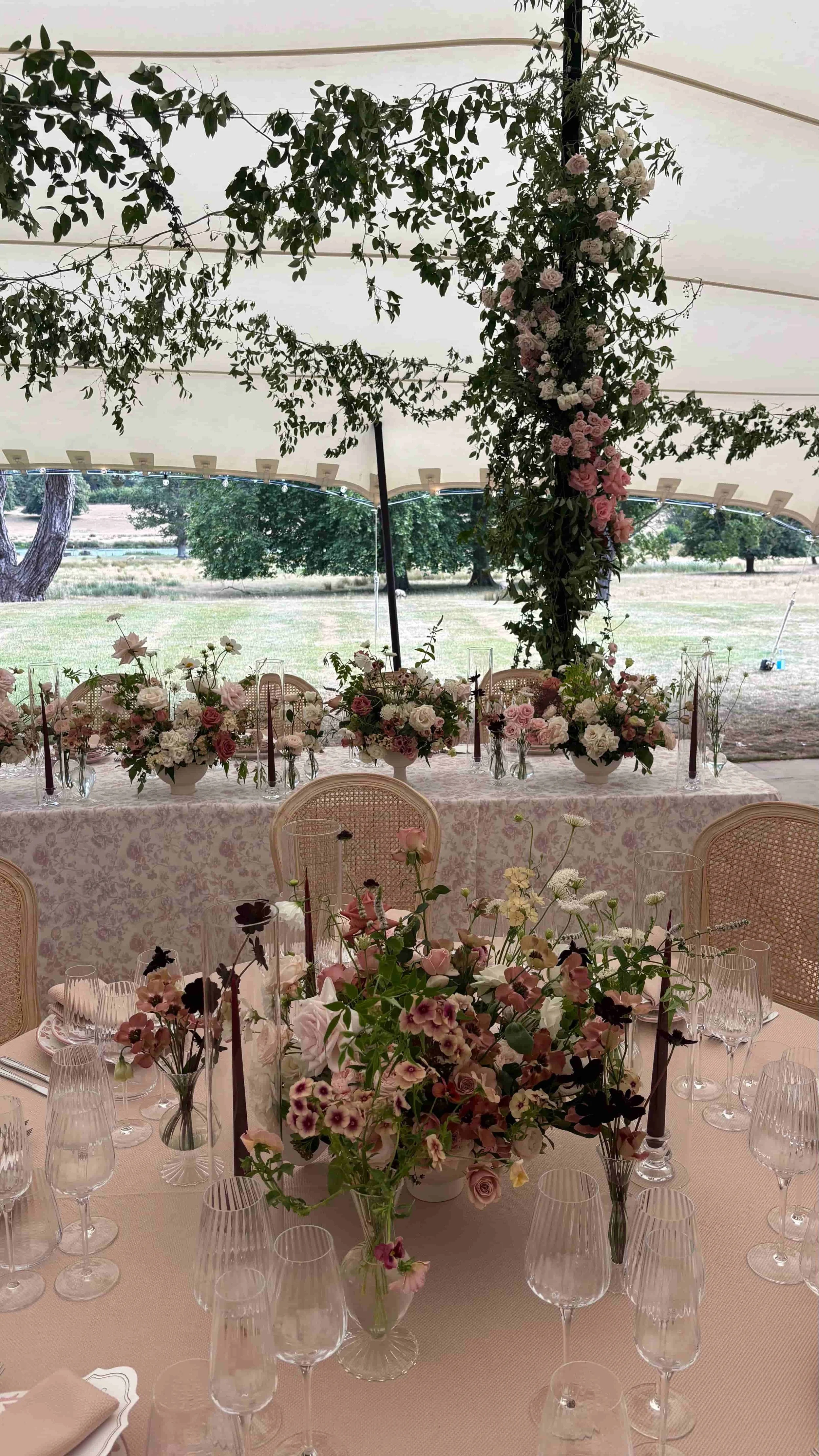 Garden-style wedding tablescape with pink flowers, patterned linens and overhead greenery at Wilderness Reserve