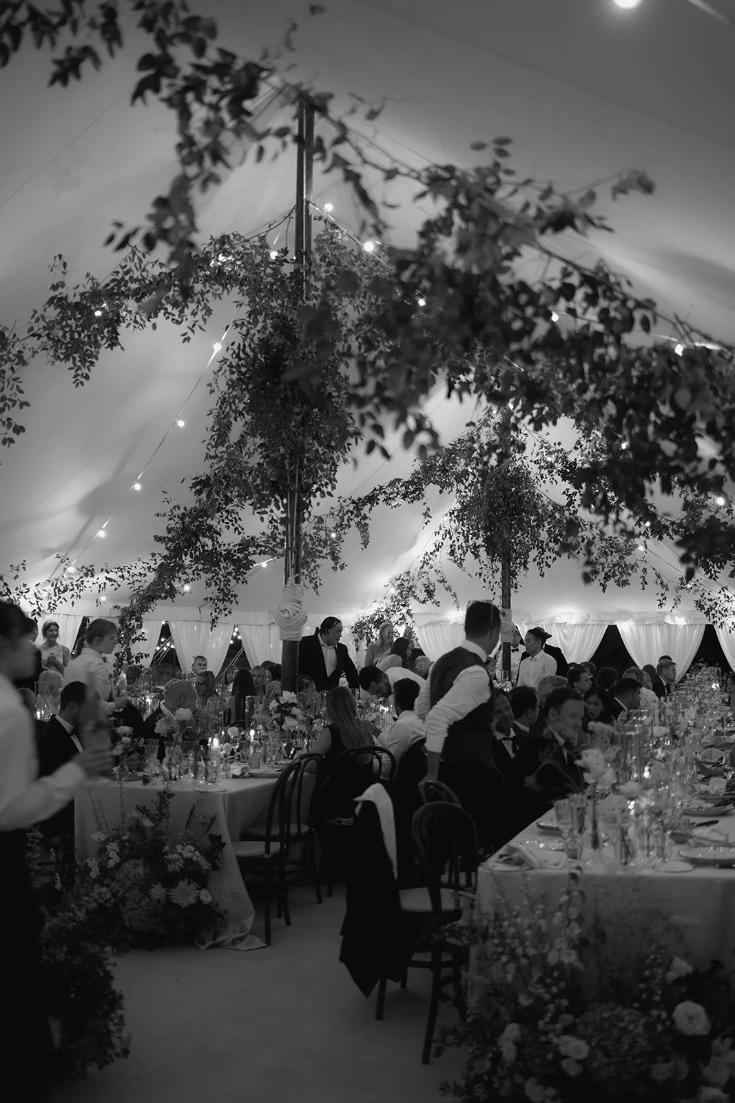 Black and white wedding reception inside a sailcloth marquee at Cornwell Manor with tables flowers and guests styled by The Botany House wedding florist
