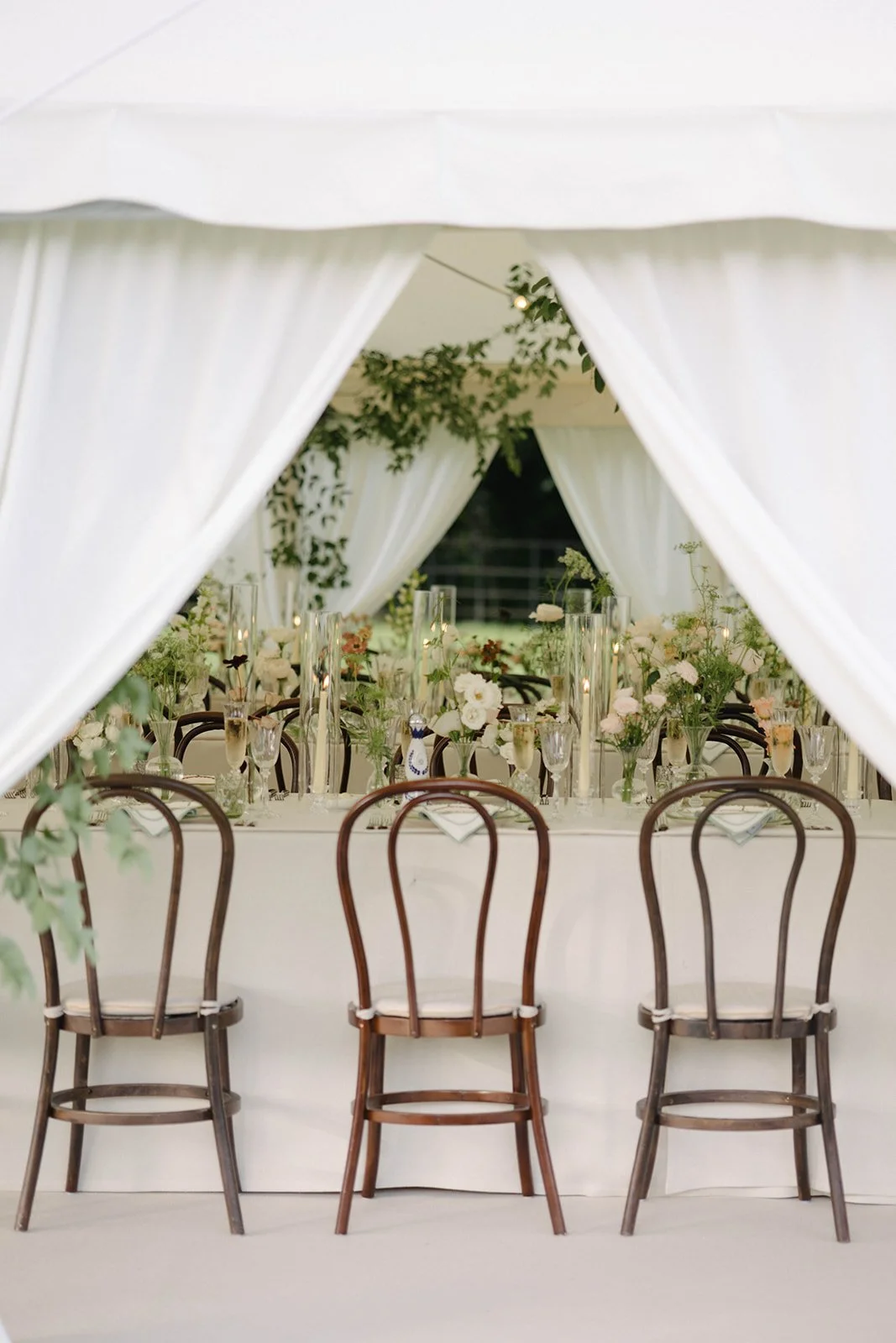 Elegant sailcloth marquee wedding reception at Cornwell Manor with luxury garden-style floral centrepieces, candles and glass vases, styled with bespoke wedding floristry by The Botany House.