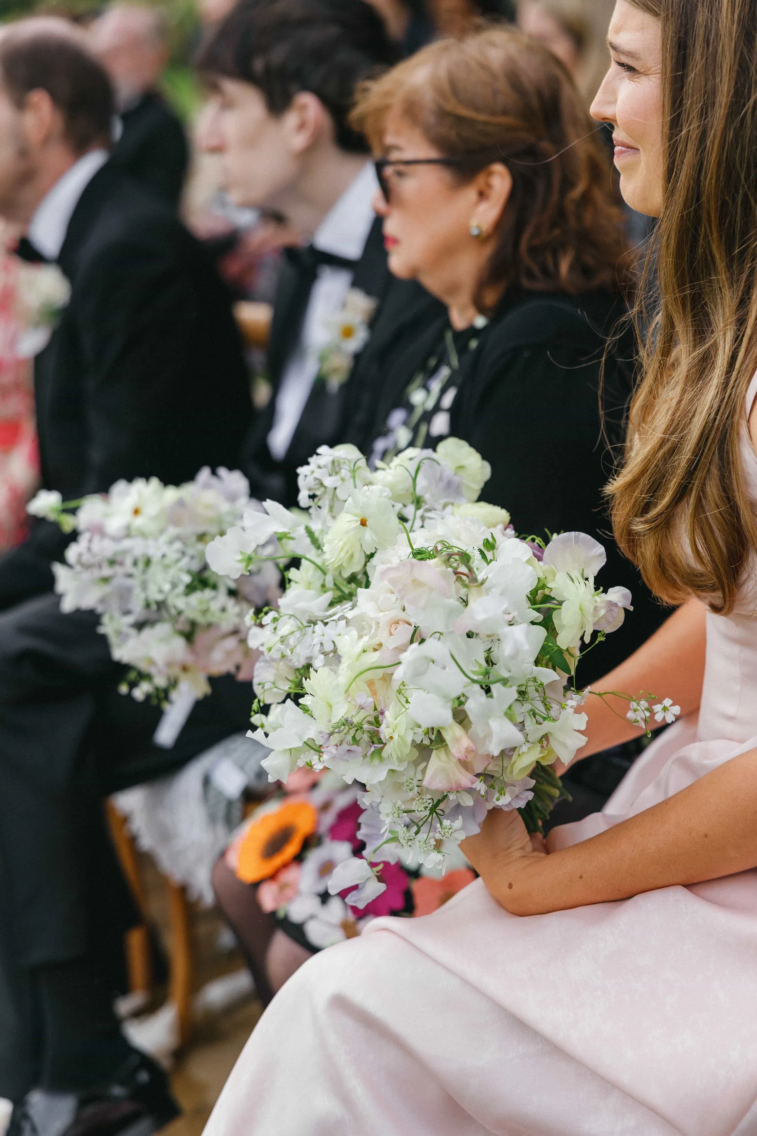 Bridesmaid in blush dress holding pastel garden-style bouquet at countryside outdoor wedding. Wilderness Reserve, Suffolk Wedding Florist The Botany House