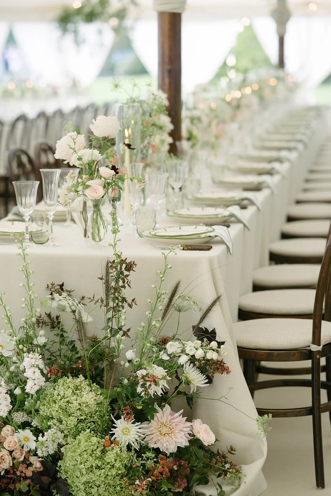 Long banquet table at a Cornwell Manor wedding with pastel floral centrepieces glassware and white linens styled with luxury garden style floristry by The Botany House