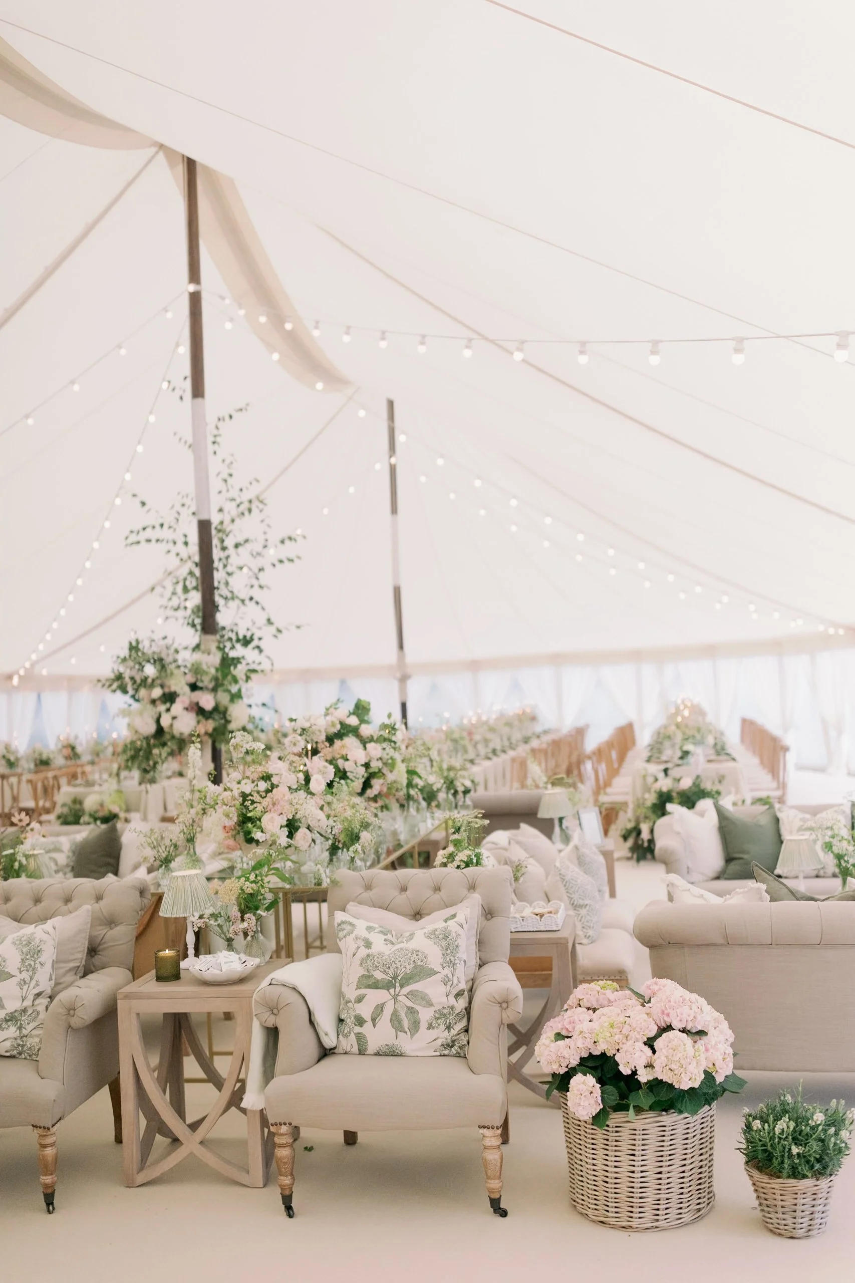 Elegant wedding reception sailcloth marquee with floral arrangements, string lights, and luxurious seating.