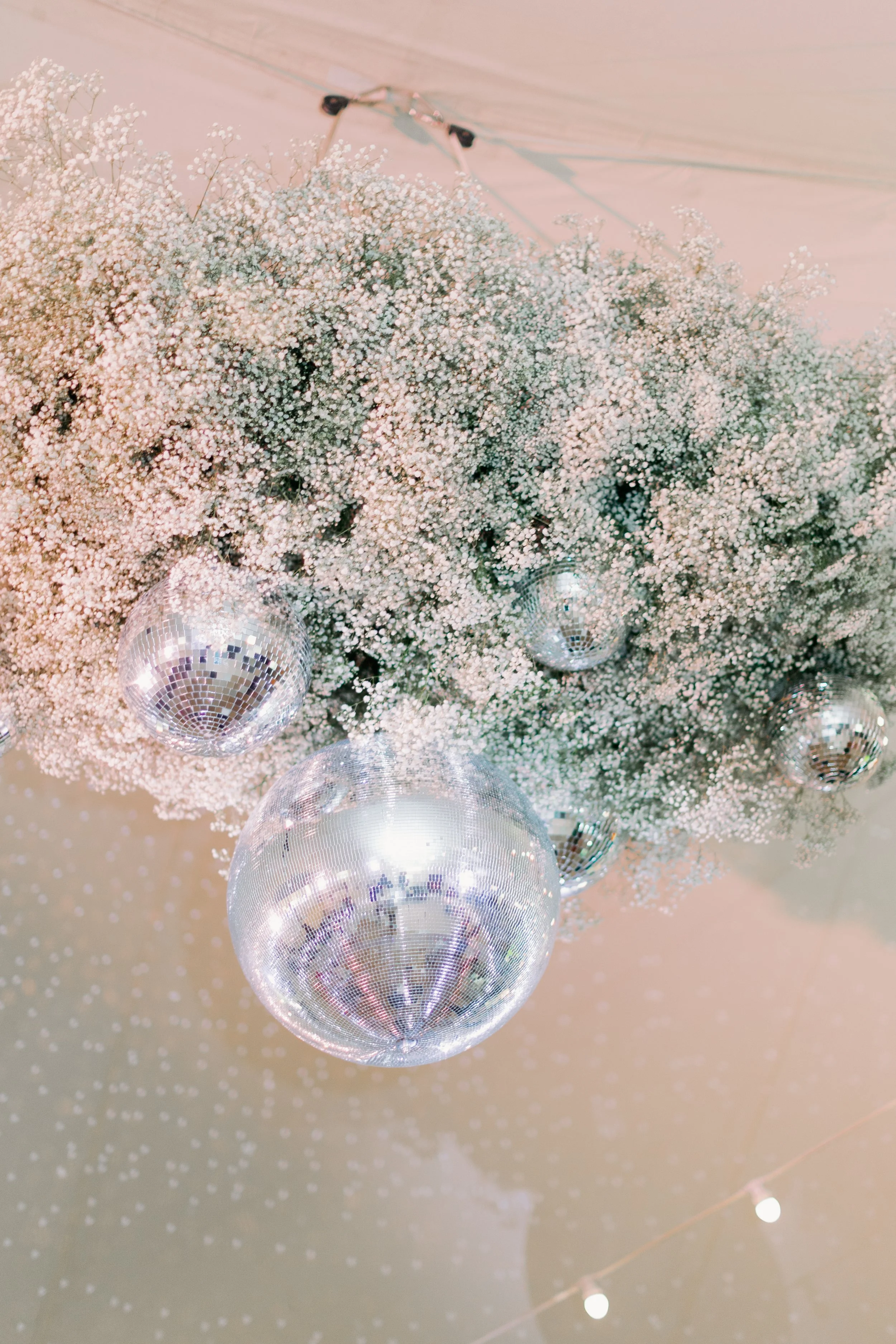 Decorative hanging floral installation of baby's breath flowers with hanging disco balls in a sailcloth marquee in Norfolk