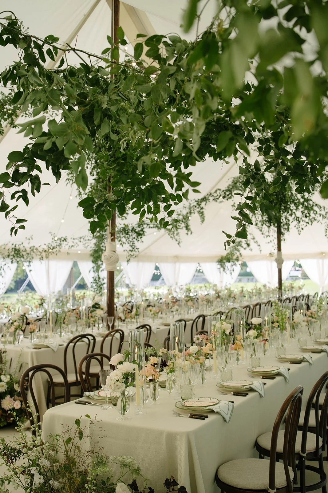 Elegant sailcloth marquee reception at Cornwell Manor with long tables white linens seasonal floral centrepieces wooden chairs and hanging greenery installations styled by The Botany House with Attabara Studio