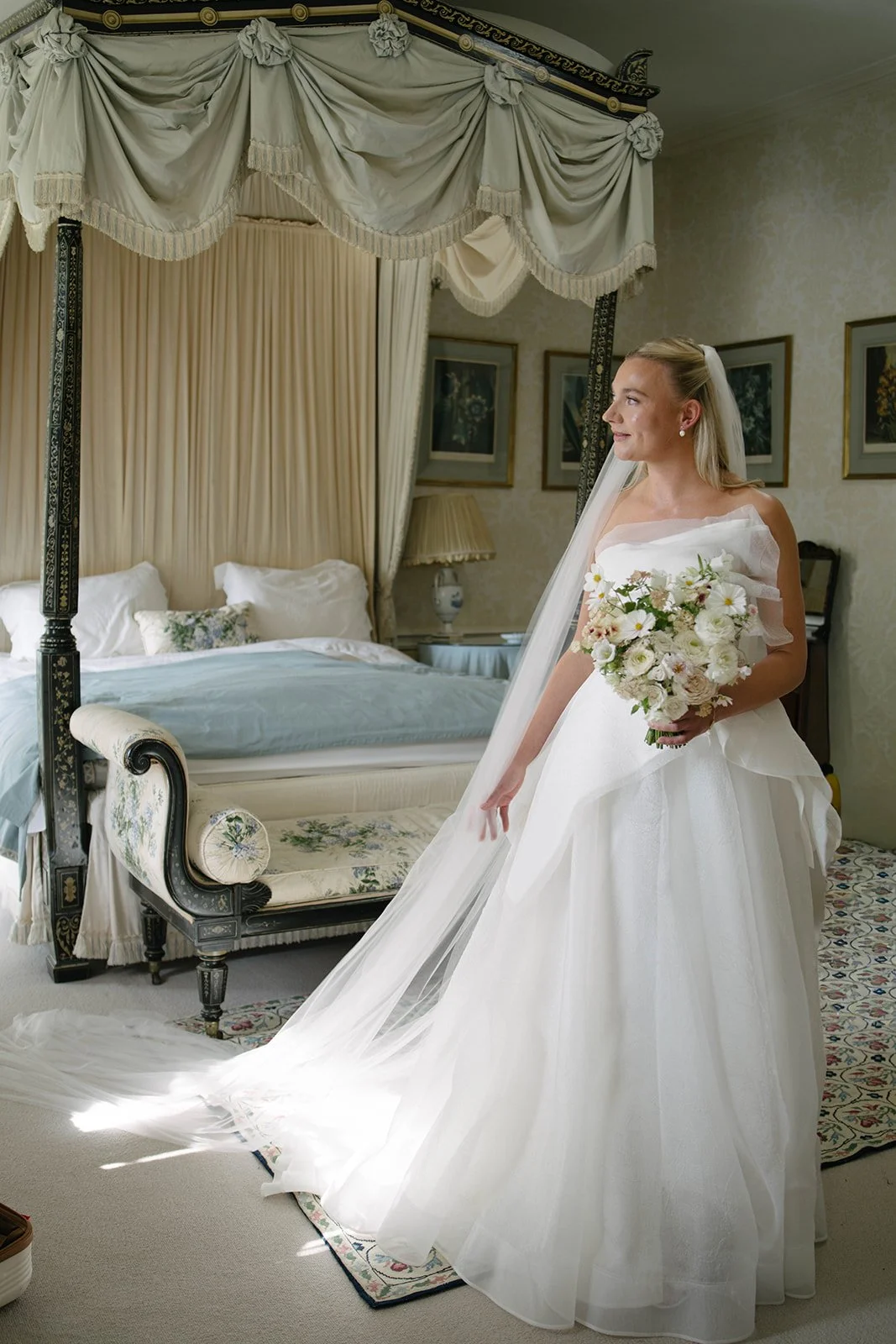 Bride in a white wedding gown holding a seasonal white bouquet at Cornwell Manor, styled with luxury garden-style wedding flowers by The Botany House in collaboration with Attabara Studio.