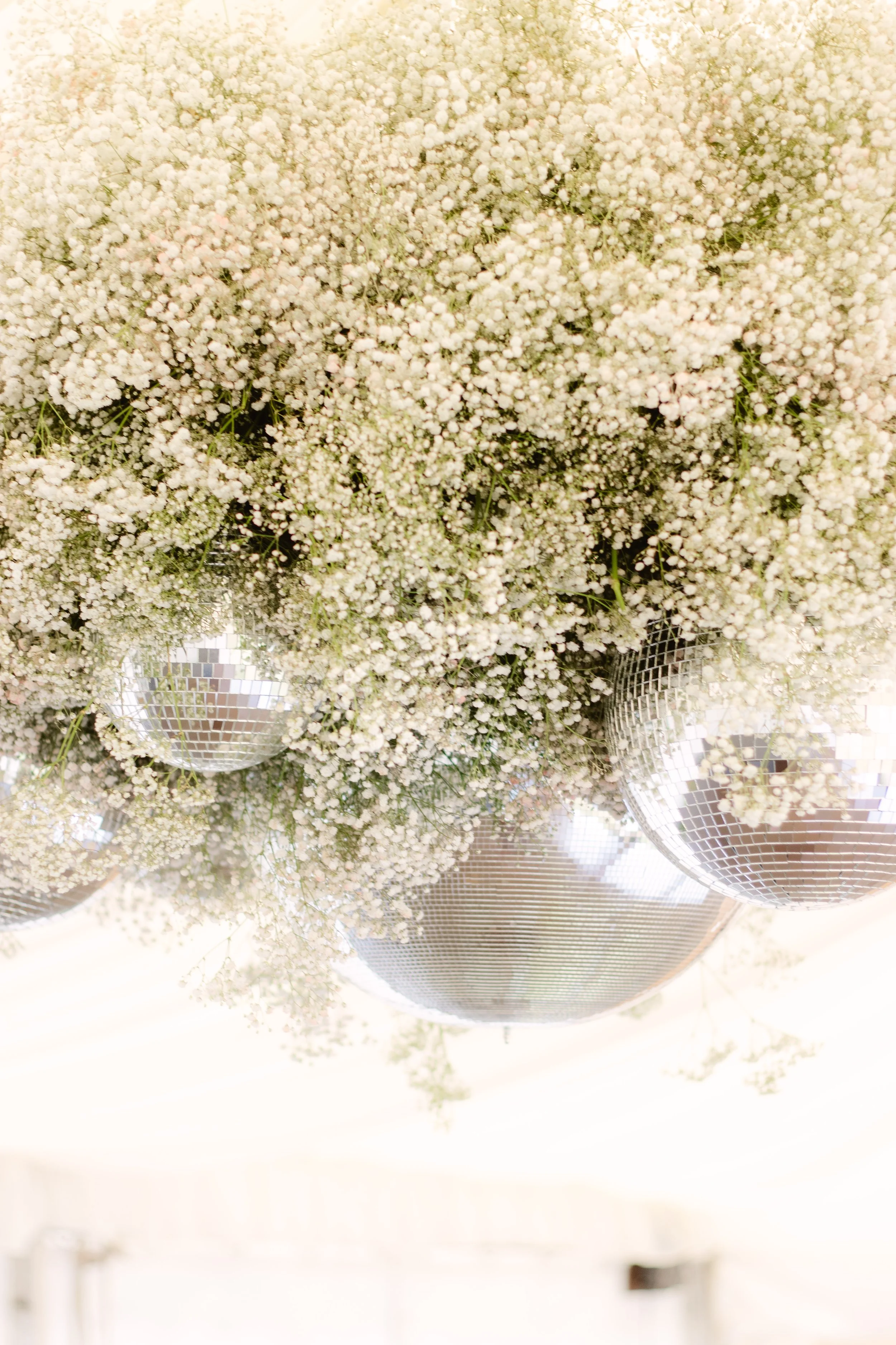 A hanging cloud of white baby's breath flowers with disco balls.