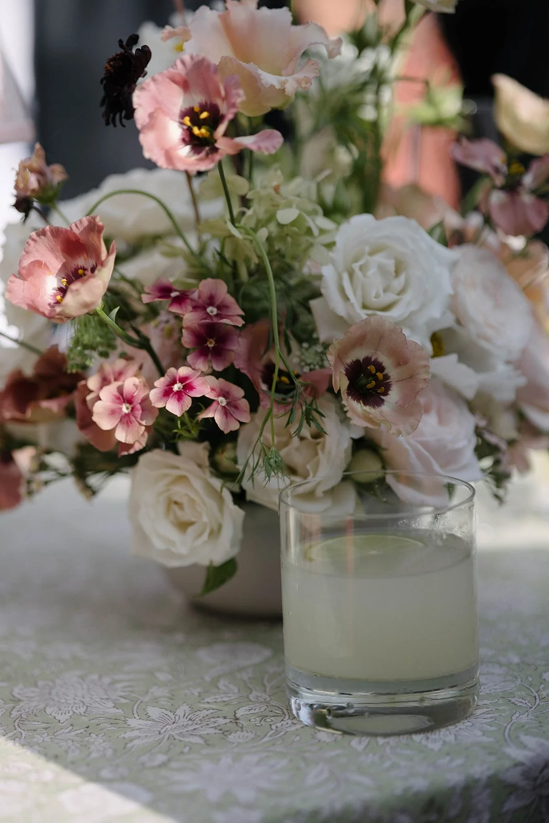 Champagne drinks reception table with blush and cream floral centrepiece at a Cornwell Manor wedding, styled with refined garden-style floristry by The Botany House, best luxury wedding florist.