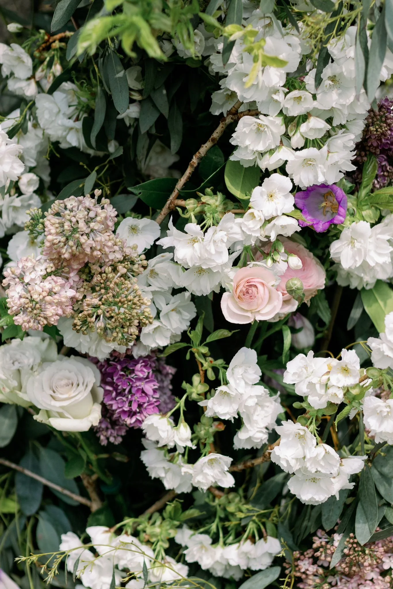 A dense arrangement of white, pink, purple, and green flowers and foliage.