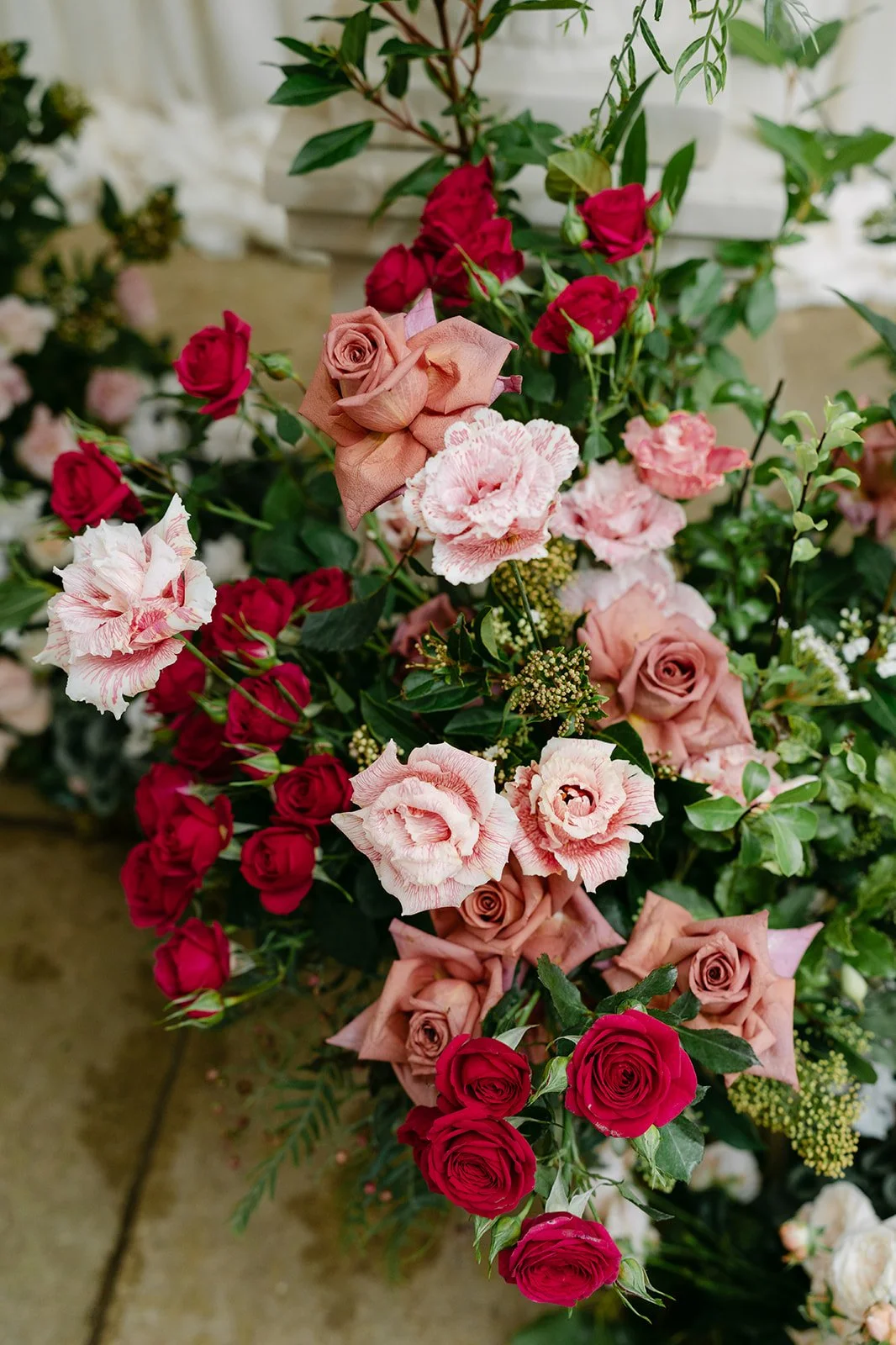 A colorful bouquet of various roses and flowers, including pink, red, and peach roses, with green foliage. The Botany House Wedding Florist Kin House