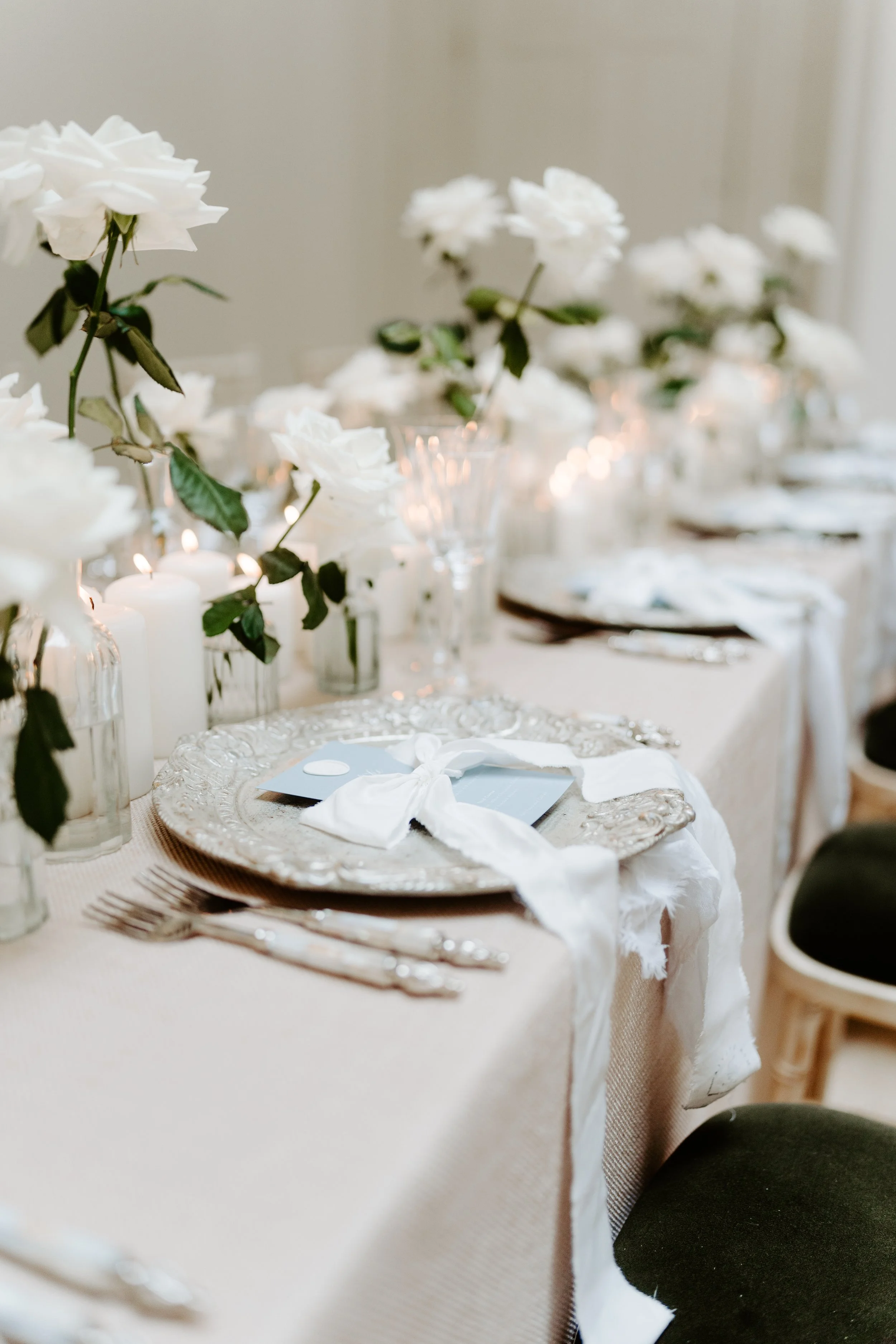 Elegant table setting with white flowers, candles, and ornate plates with white napkins