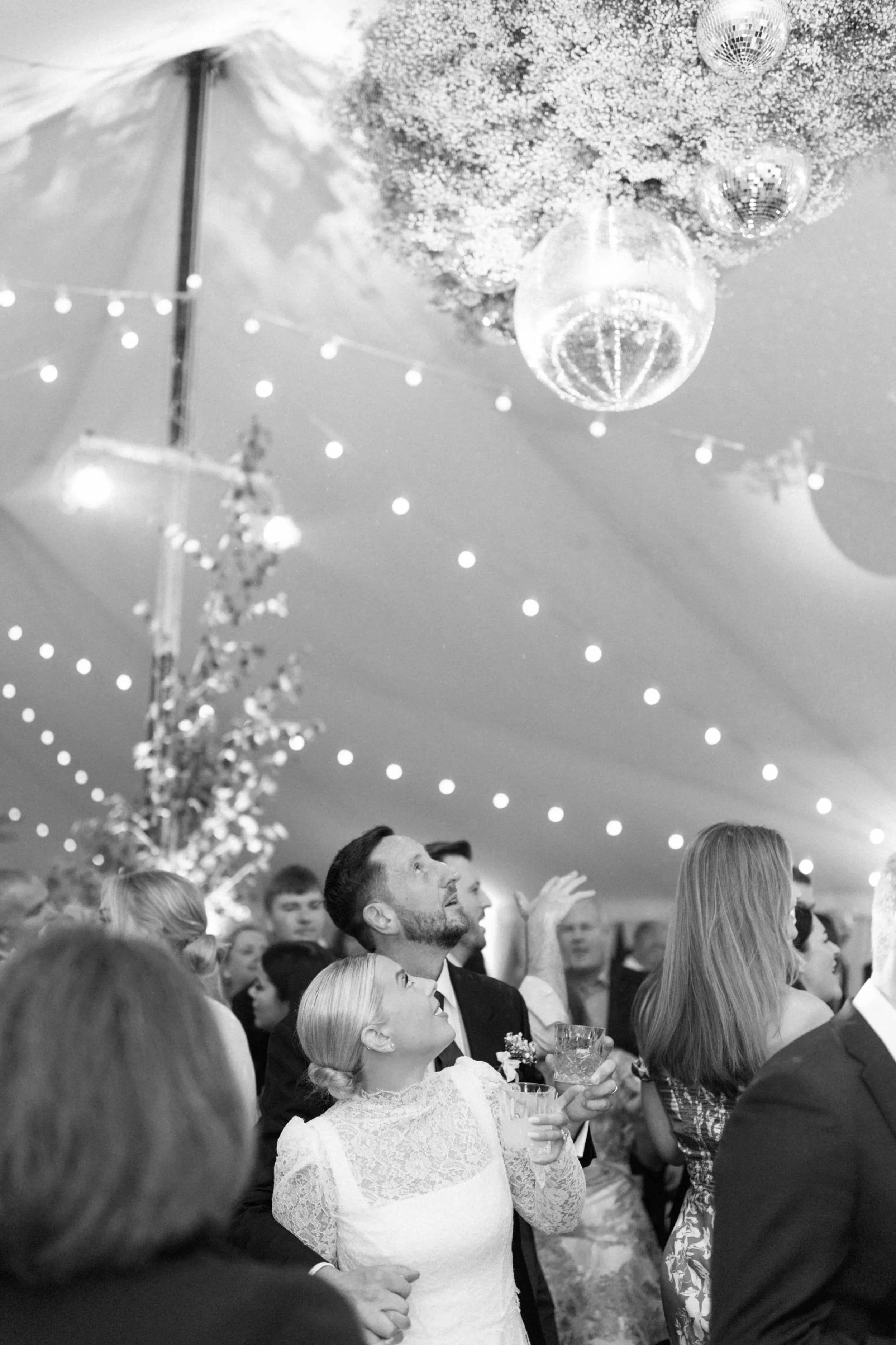 People at a party or celebration looking at hanging disco balls and lights on the ceiling.
