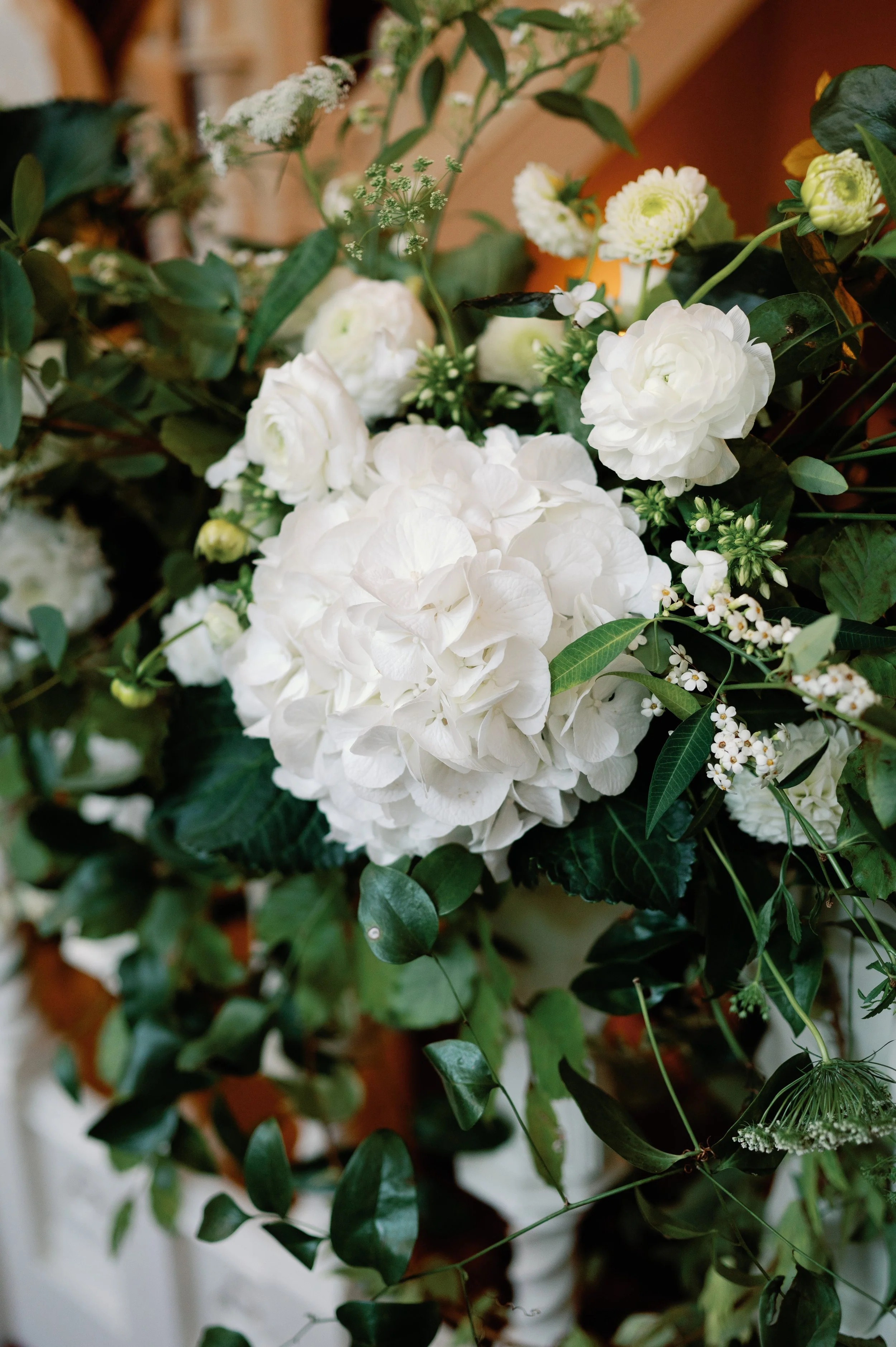 A bouquet of white flowers including hydrangeas, roses, and various greenery.