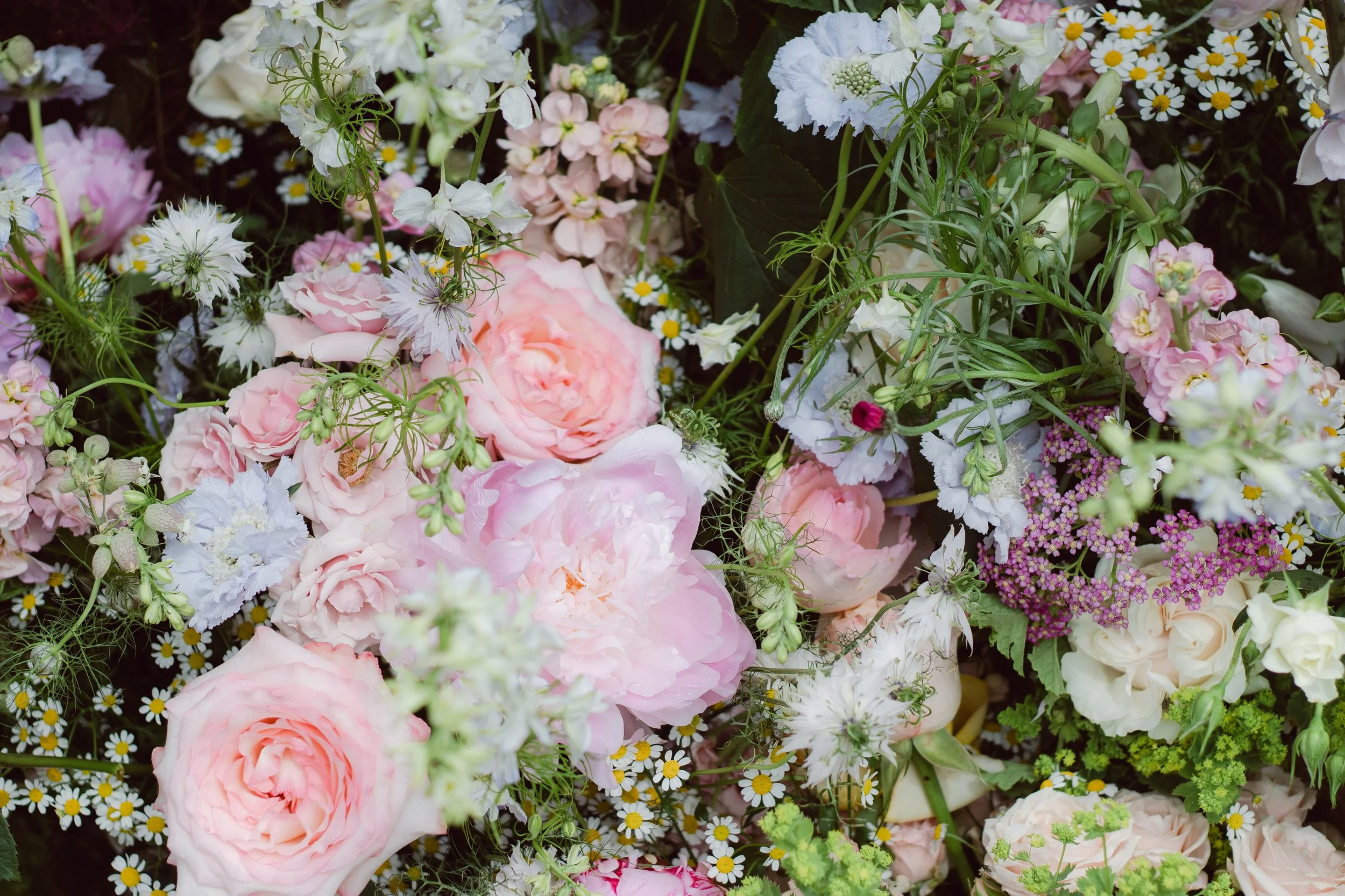 A colorful assortment of various flowers, including pink roses, white daisies, and purple and white blossoms.