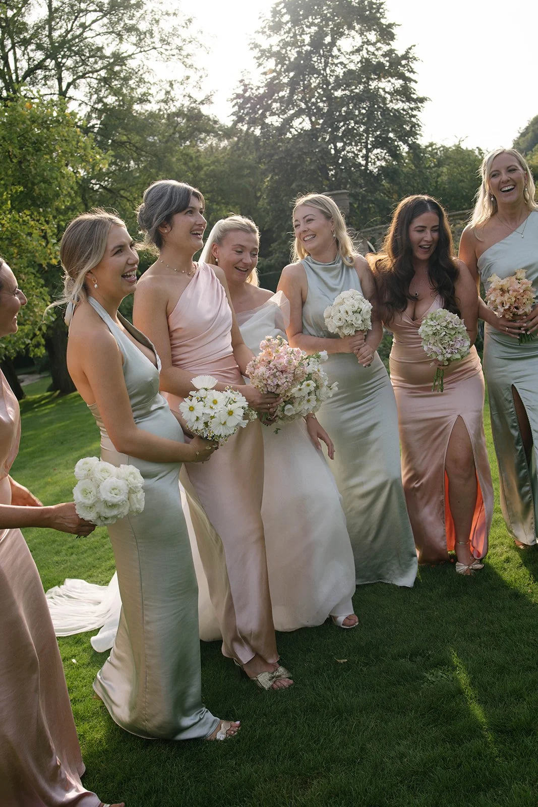 Bridesmaids in pastel dresses holding blush and cream bouquets at a Cornwell Manor wedding, styled with luxury garden-style wedding flowers by The Botany House, best luxury wedding florist.
