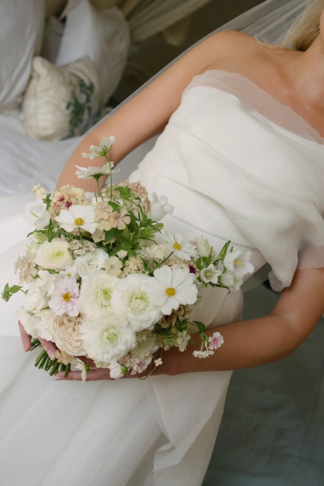 Bride holding a soft blush and white seasonal bouquet at Cornwell Manor, designed in a luxury garden style by The Botany House, best luxury wedding florist.