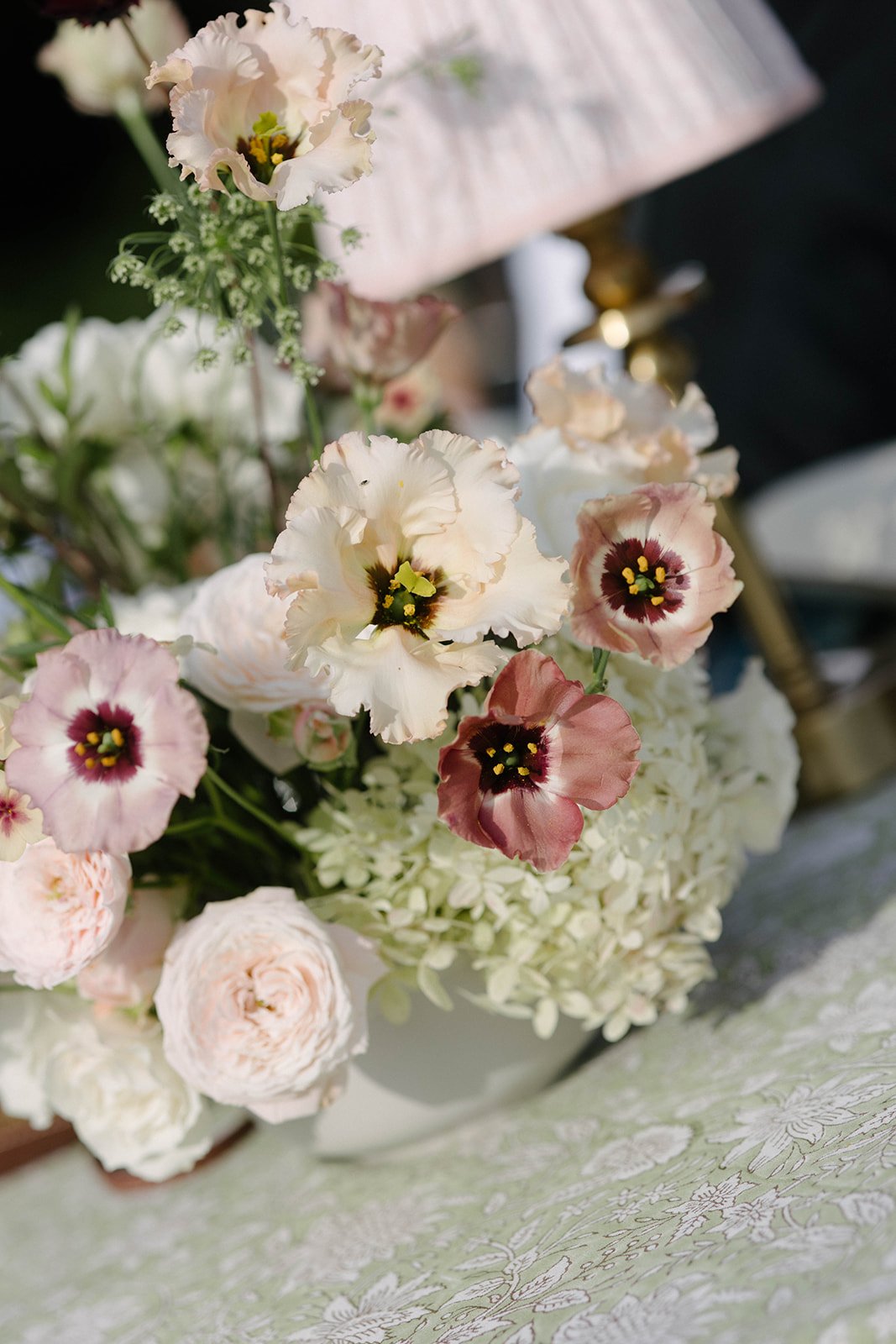 Close-up of a luxury garden-style table arrangement of blush, cream and white seasonal flowers at a Cornwell Manor wedding, styled with bespoke wedding floristry by The Botany House.
