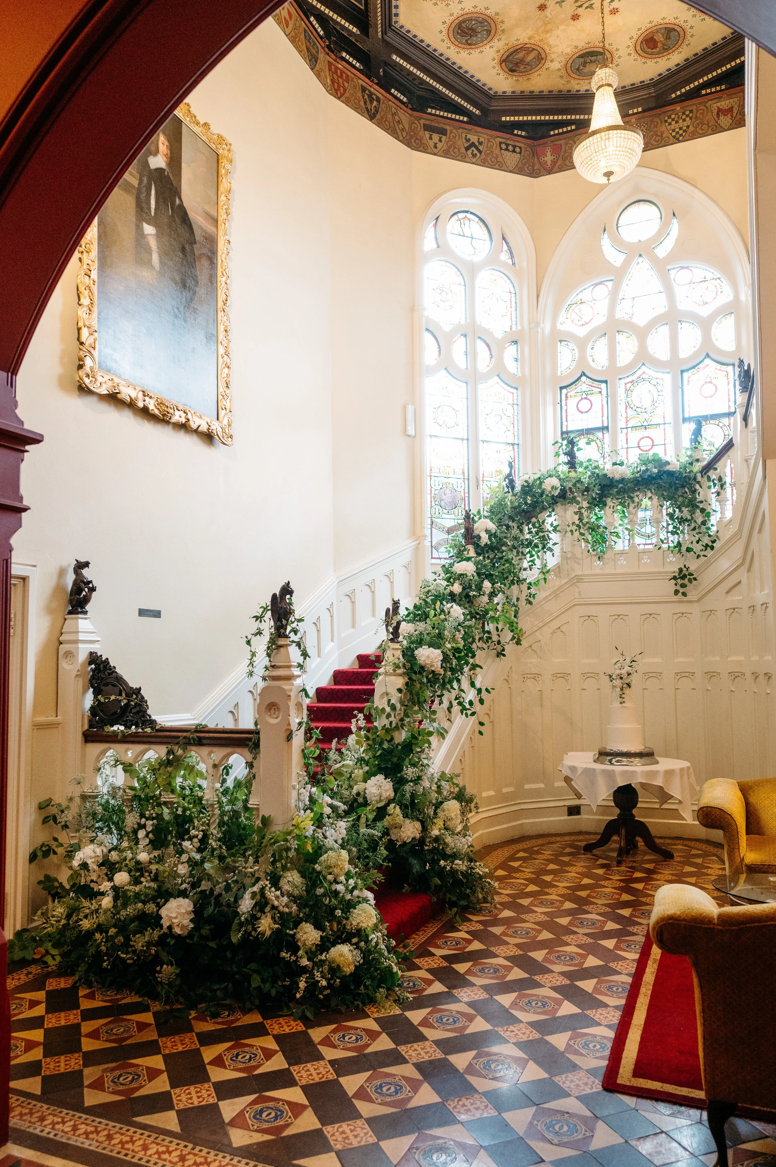 Elegant interior with a stained glass window, floral staircase decoration, and vintage furniture.