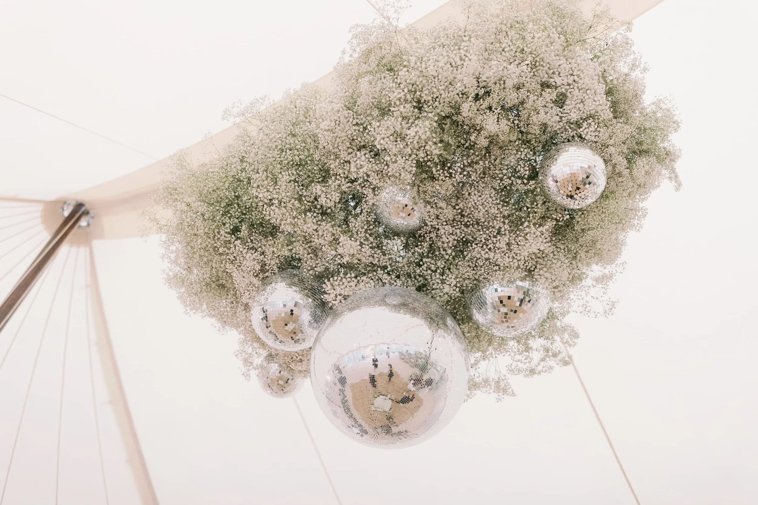 A ceiling decorated with white baby's breath flowers and hanging disco balls.