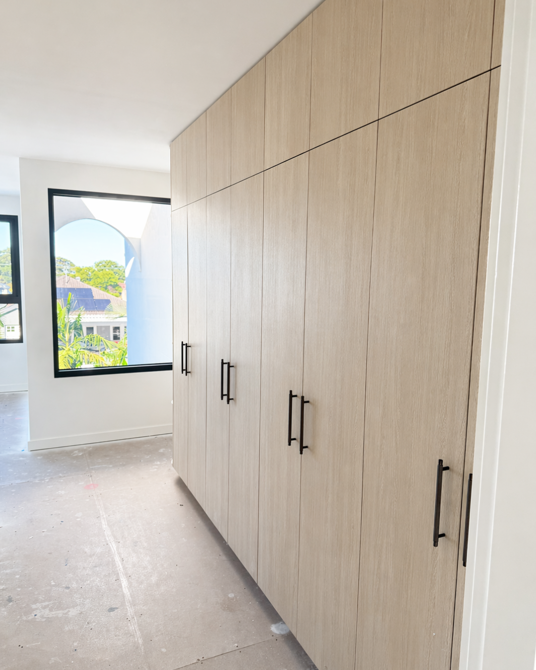 Built-in wardrobe joinery in a Haymet Street duplex with timber finish and black handles during final stages