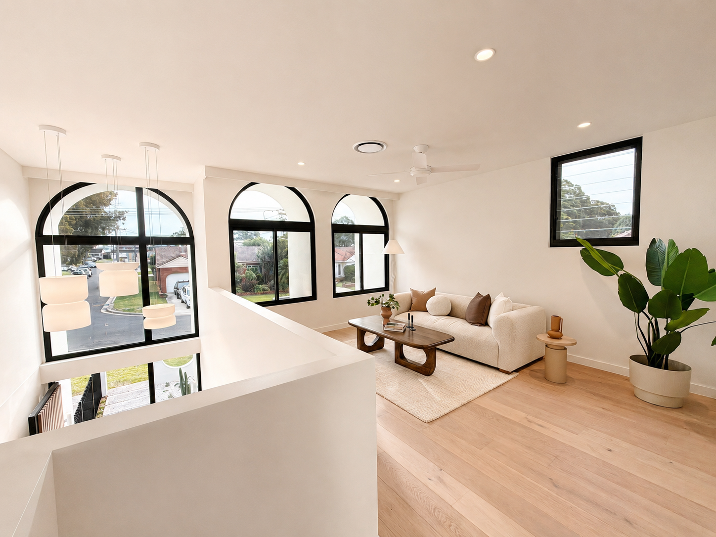 Upper living area of the Kirrawee duplex featuring arched windows, natural light, timber flooring and contemporary interior finishes.