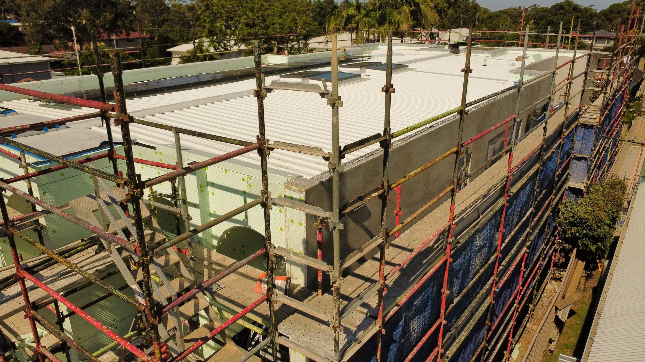 Duplex under construction in Kirrawee Sydney showing metal roof installation and external finishes underway by Caton Constructions