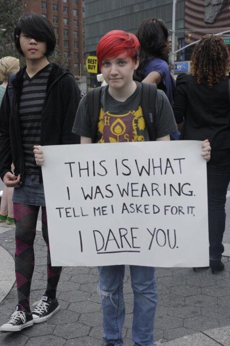 Image description: Picture of a person at a protest holding a sign ‘This is what I was wearing. Tell me I asked for it. I dare you.’ 