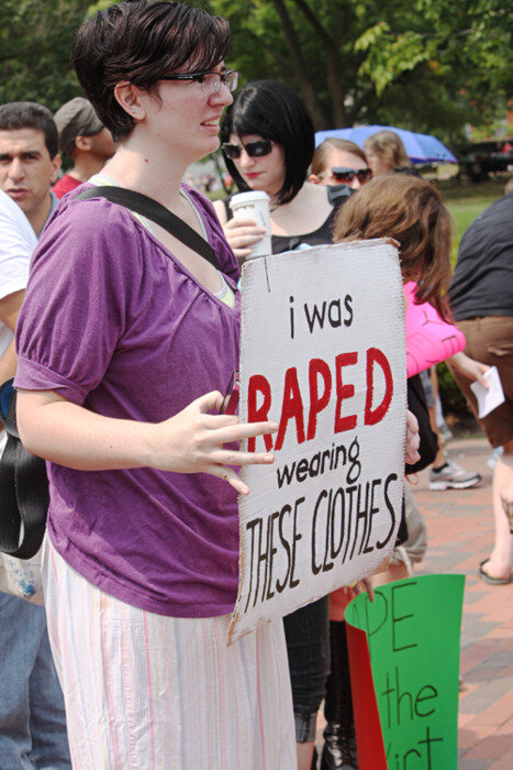  Image description: Person at a protest wearing pajamas holding a sign that reads ‘I was raped wearing these clothes’ 