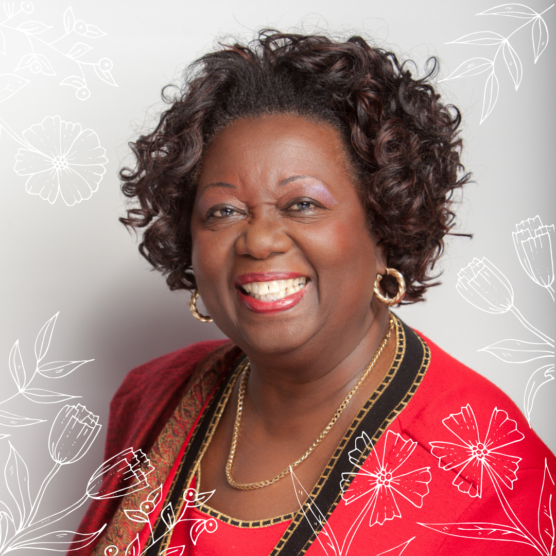 An image of the Honorable Jean Augustine, a smiling Black woman with short, curly hair, wearing a red top.