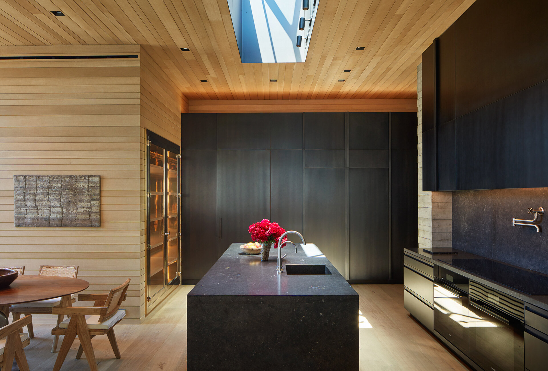  Custom luxury home general contractor built modern private residence in the Pacific Palisades neighborhood of Los Angeles featuring stunning dining room and kitchen with wood wall panels and matte black cabinets.  