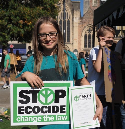 chica con pancarta de la campaña y mostrando su certificado de Protectora de la Tierra