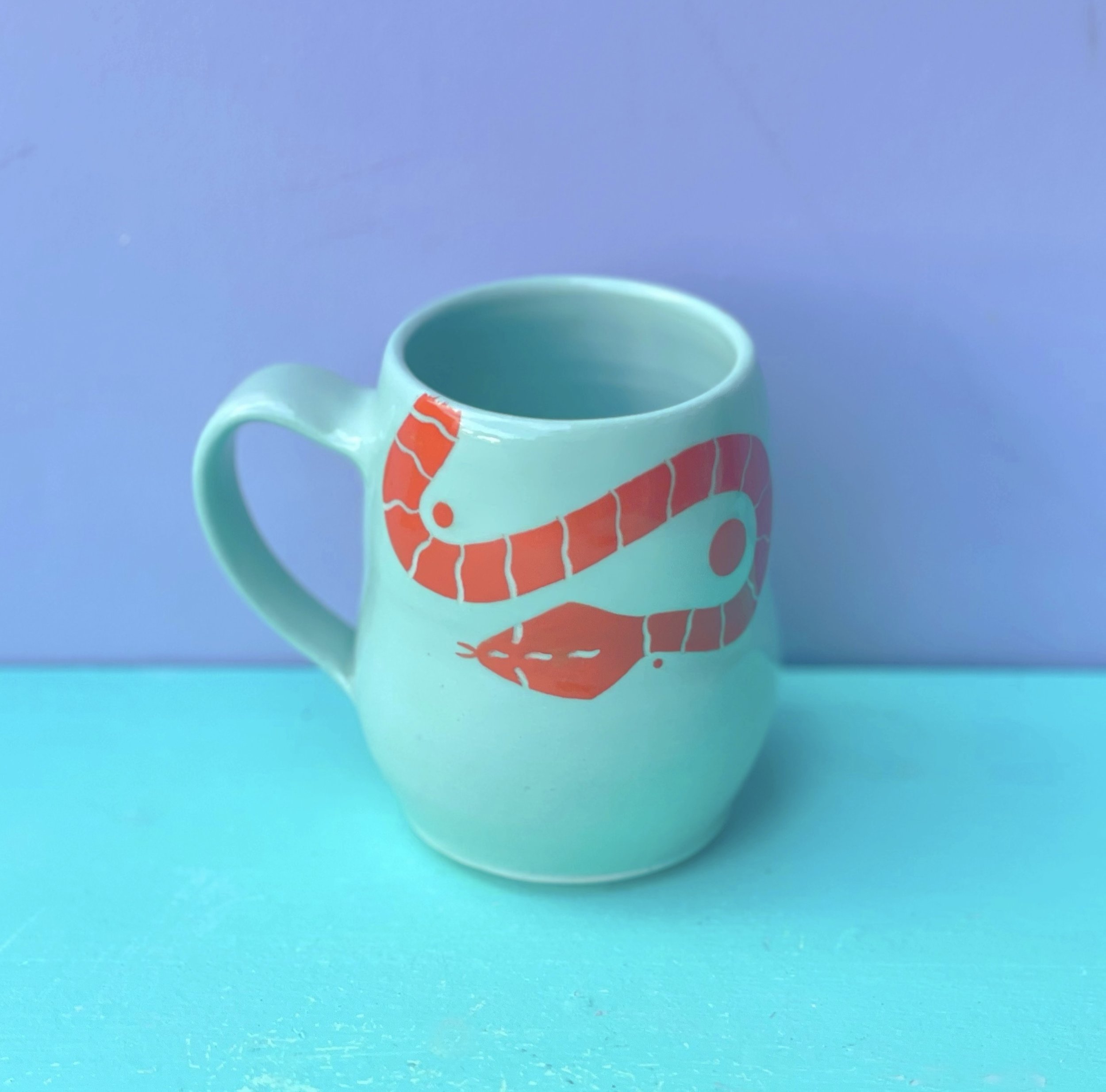 mint green mug with orange snake