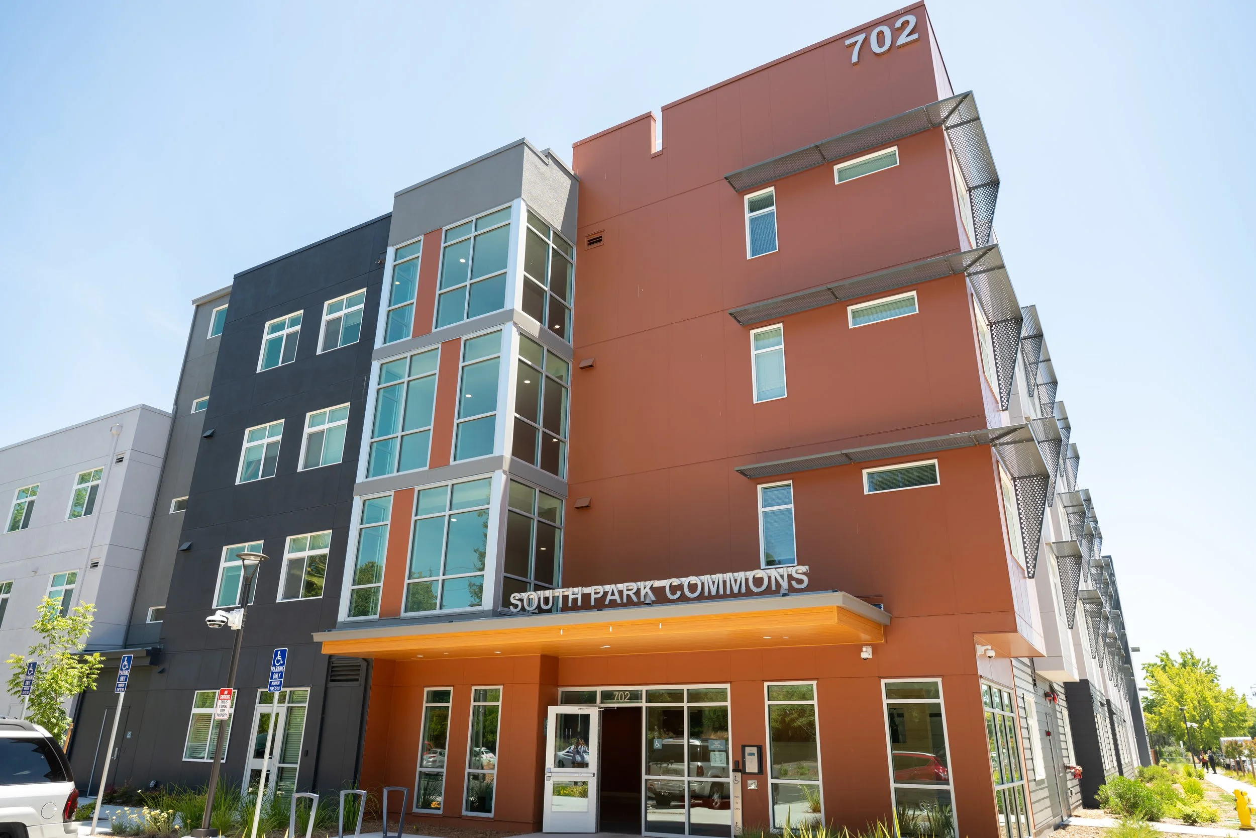 An exterior photo of a copper-color four-story apartment building on a sunny day